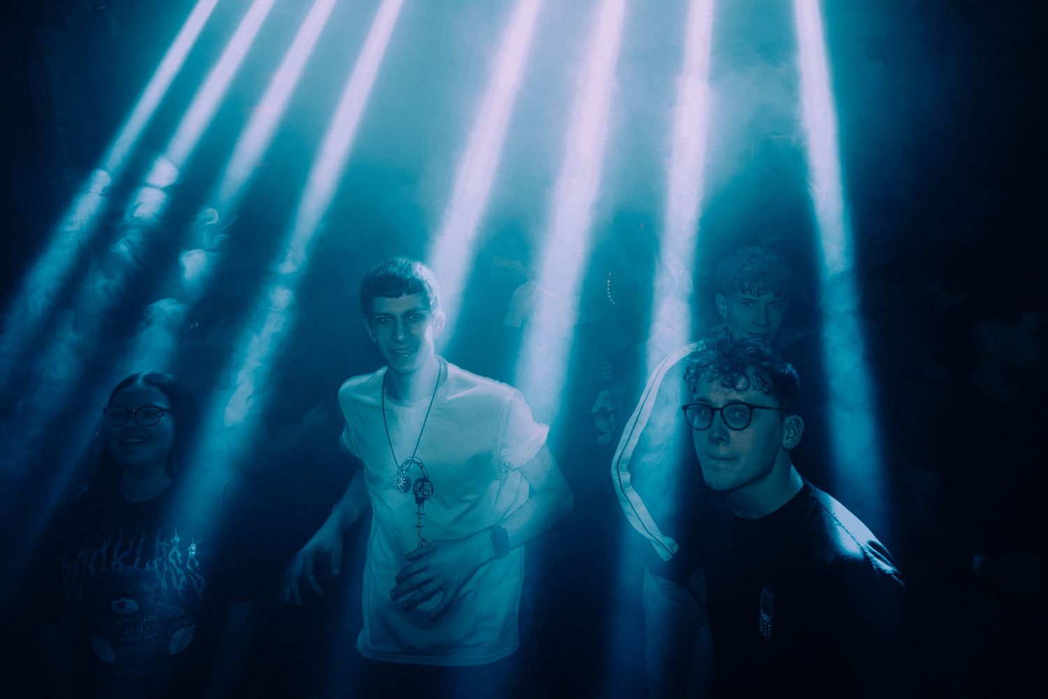 People performing on stage illuminated by dramatic blue and white spotlights creating an atmospheric concert scene.