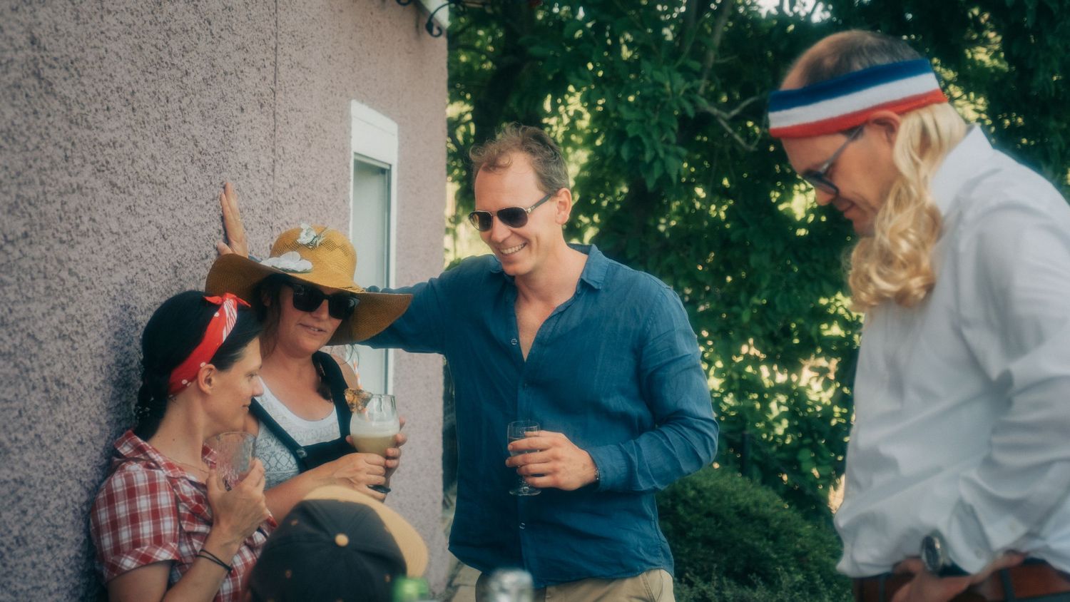 Guests mingle and socialize at an outdoor daytime party on a patio.