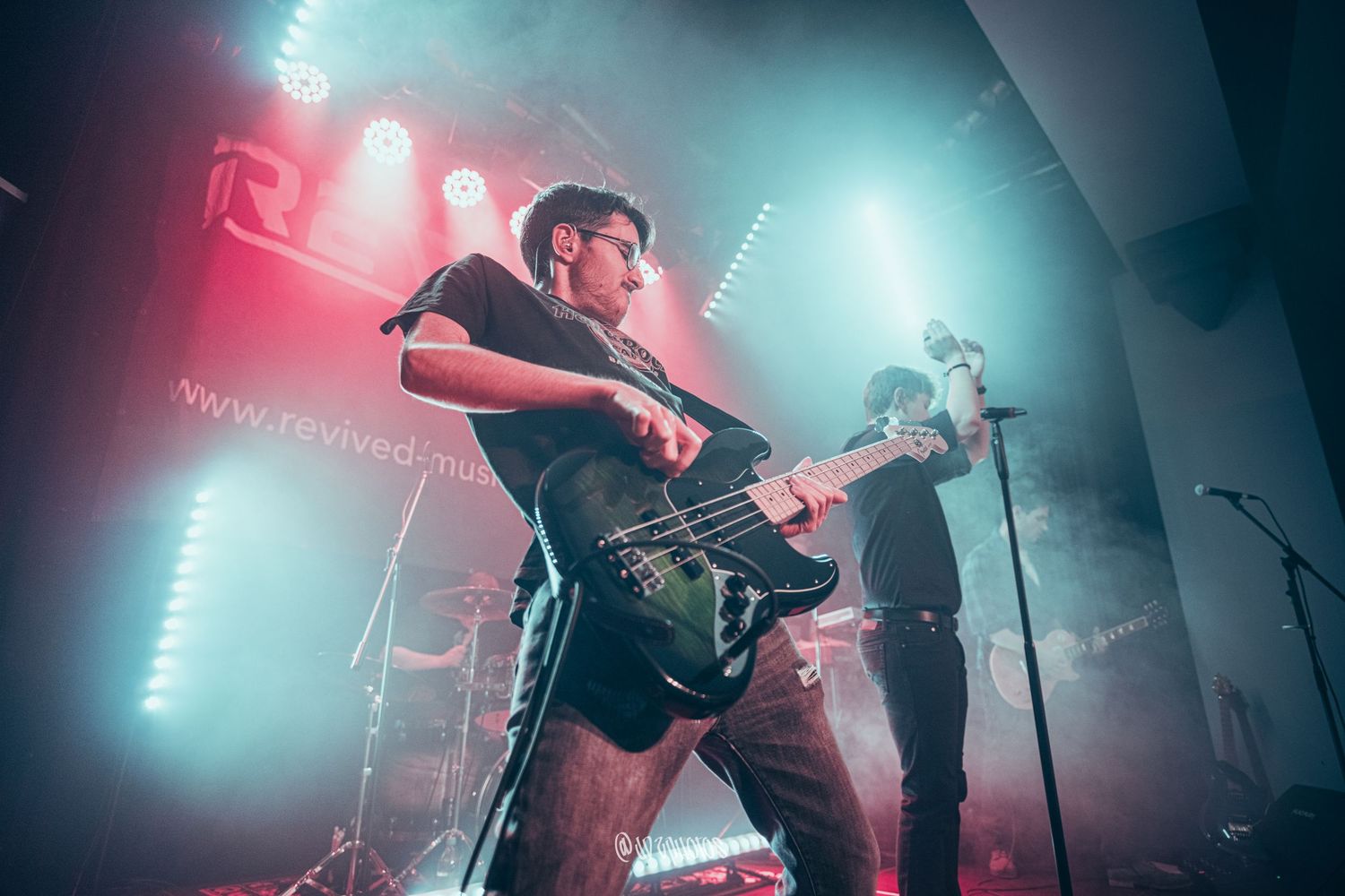 Live music performance with teal and red stage lighting creating atmospheric mood.