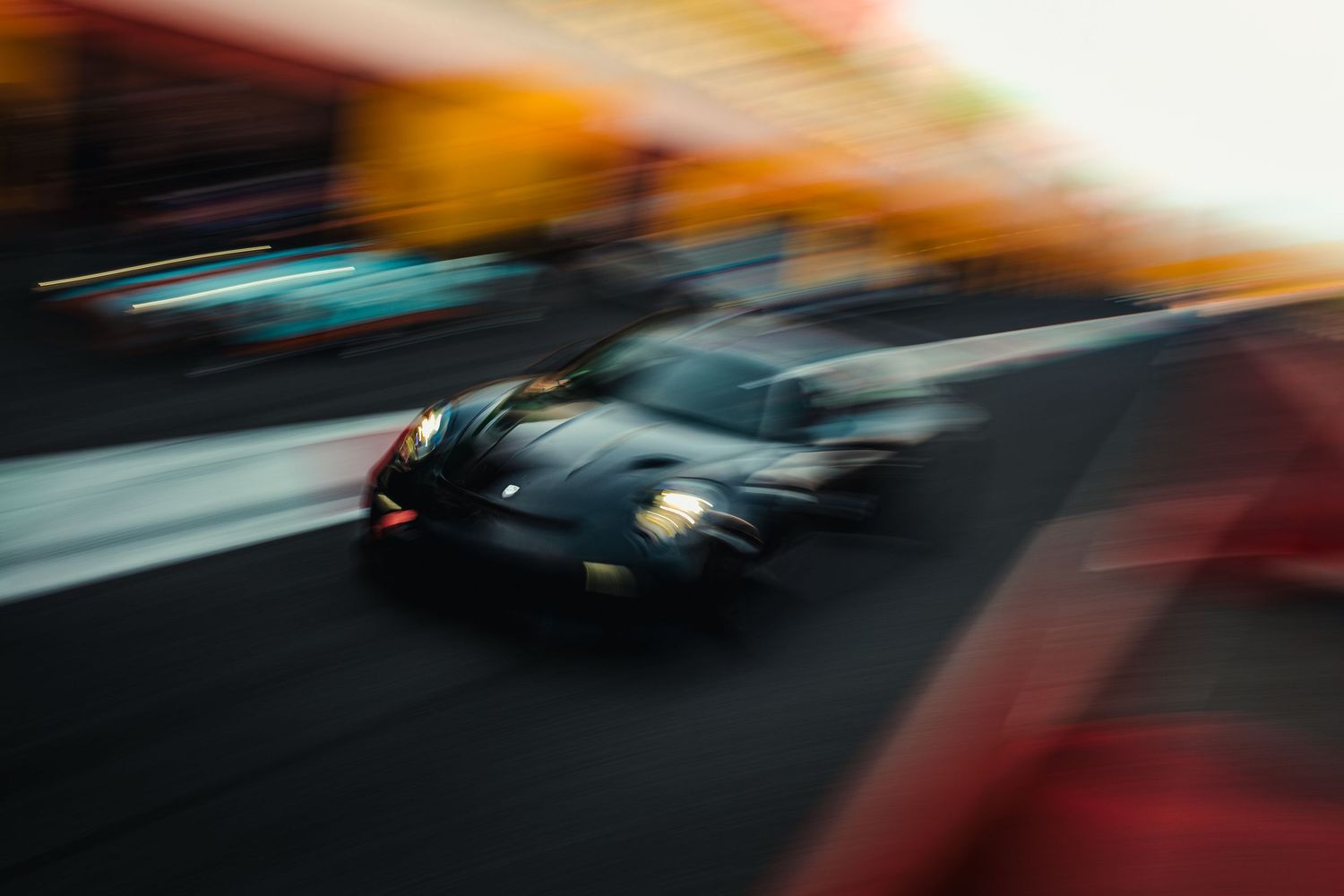 A dark racing car speeds along a track, captured with motion blur emphasizing its high velocity in dramatic lighting.