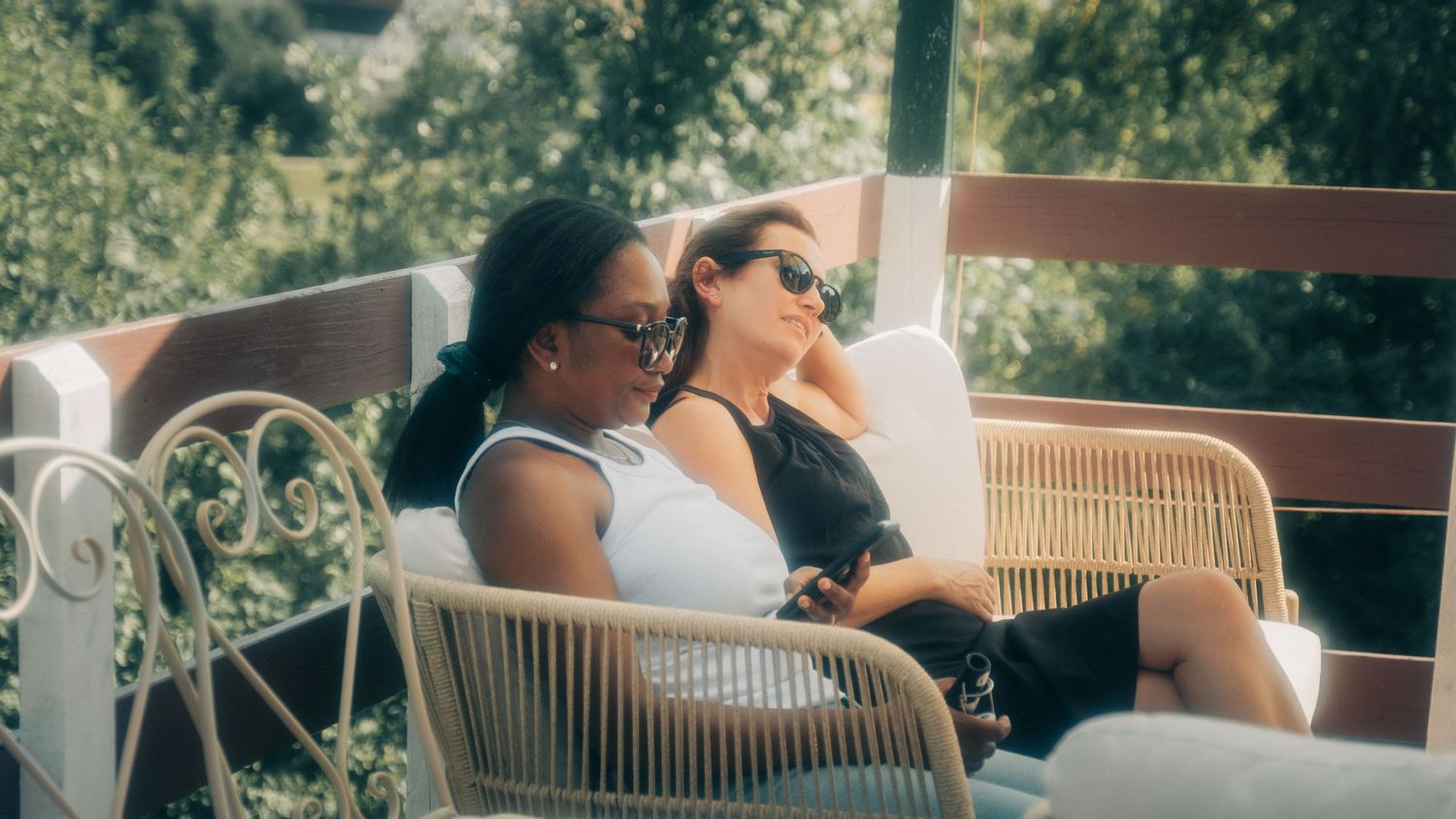 People relaxing on outdoor patio furniture overlooking mountain scenery.