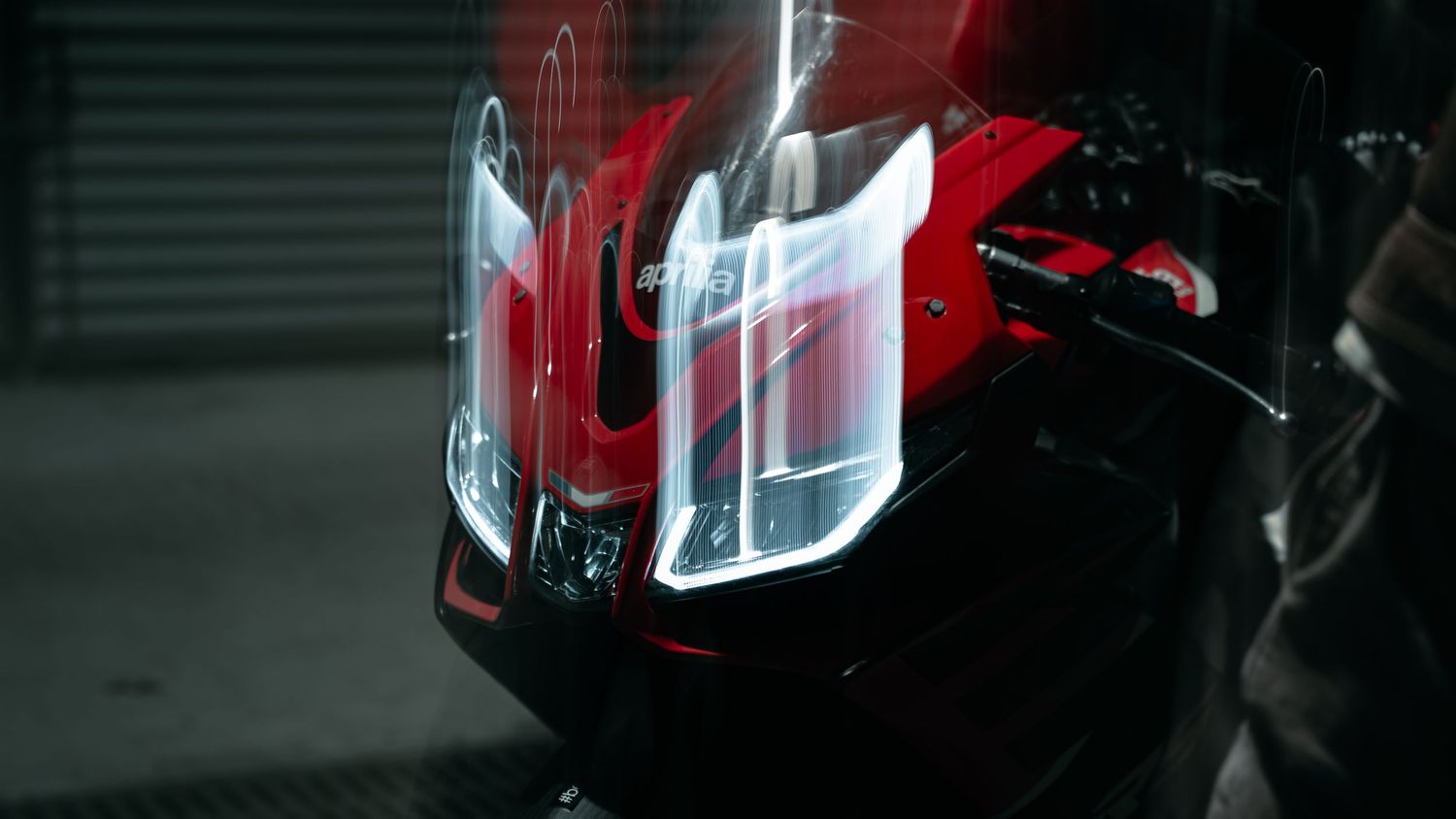 Red sports bike headlight detail shot in dark atmospheric lighting.