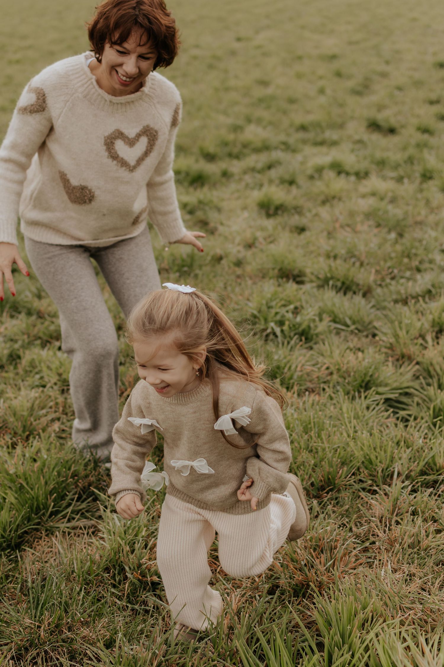 Kinder in kuscheligen Pullovern spielen zusammen auf einem grasbewachsenen Feld.