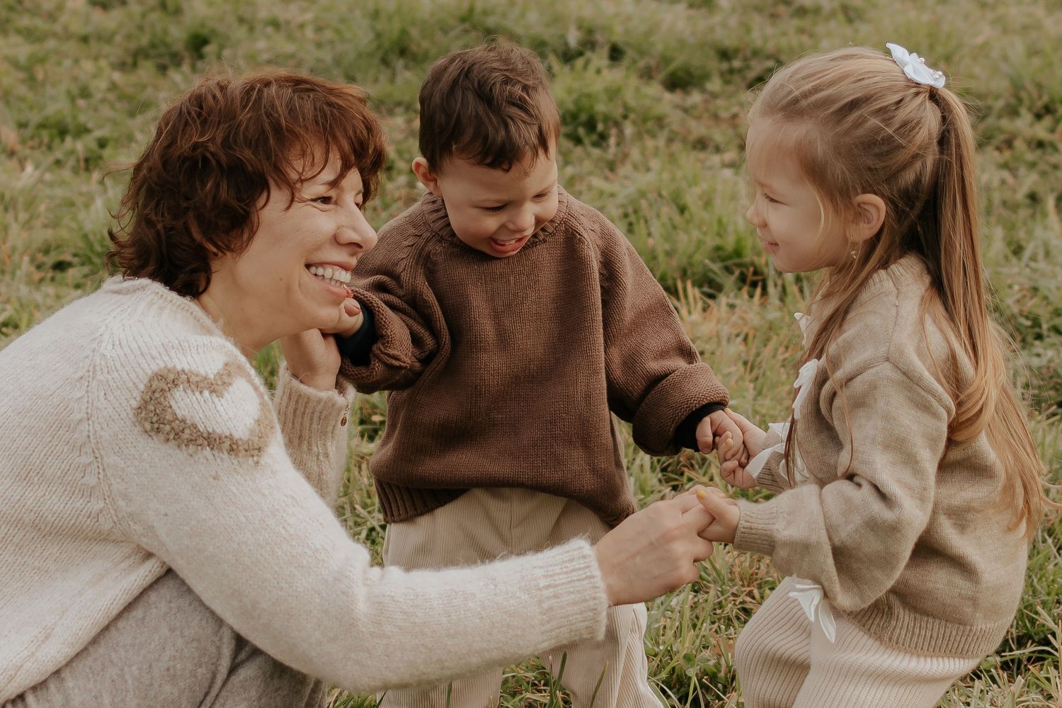 Die Familie teilt einen fröhlichen Moment zusammen auf dem Feld und trägt koordinierte neutrale Outfits.
