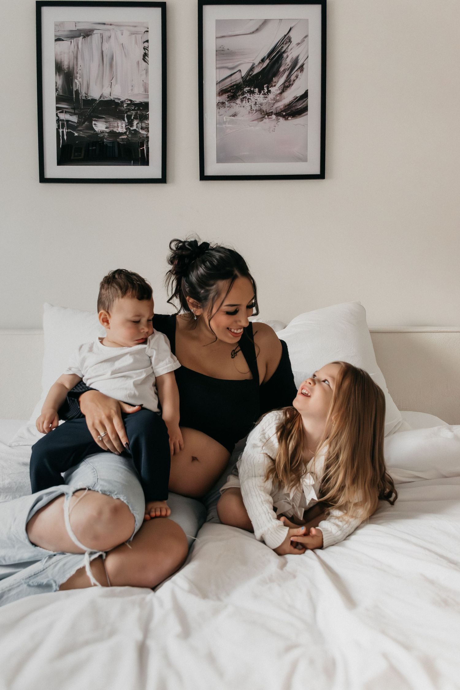 Lifestyle-Fotografie-Session, die spielerische Familieninteraktionen auf weißer Bettwäsche zeigt.
