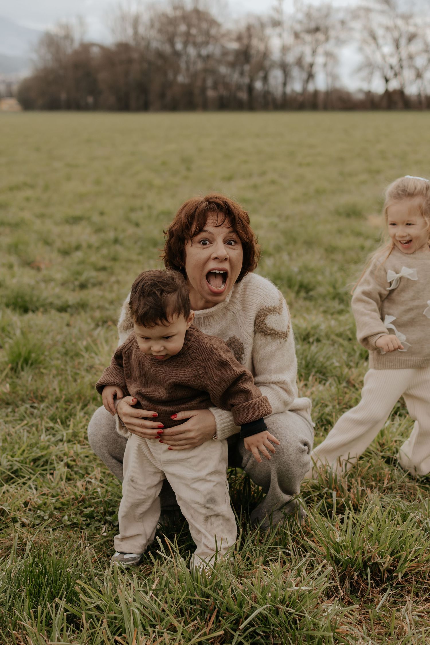 Spieleriste Familieninteraktion, die während der goldenen Stunde auf einem grasbelasten Feld festgehalten wird.