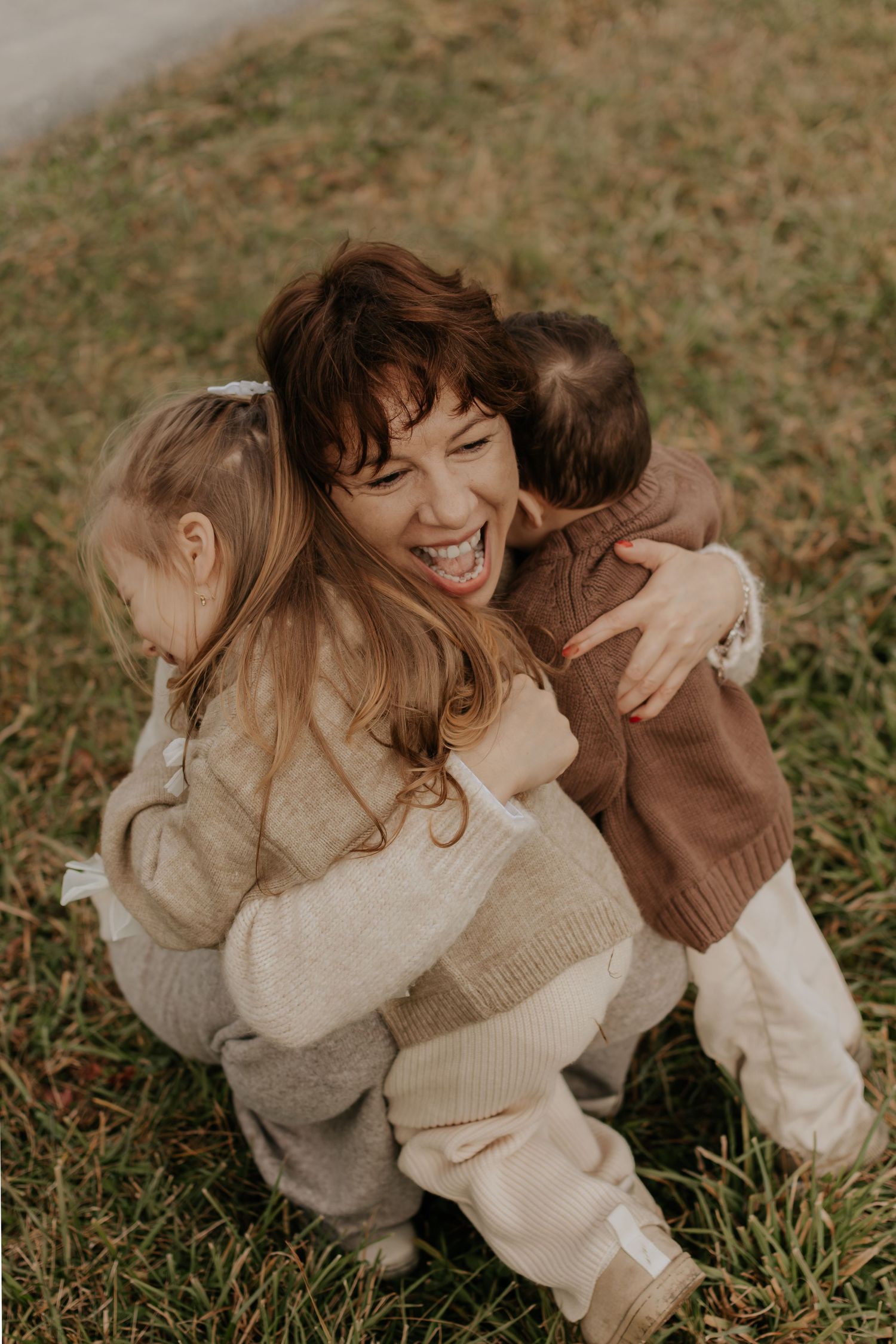 A joyful family moment captured on grass with warm autumn tones.
