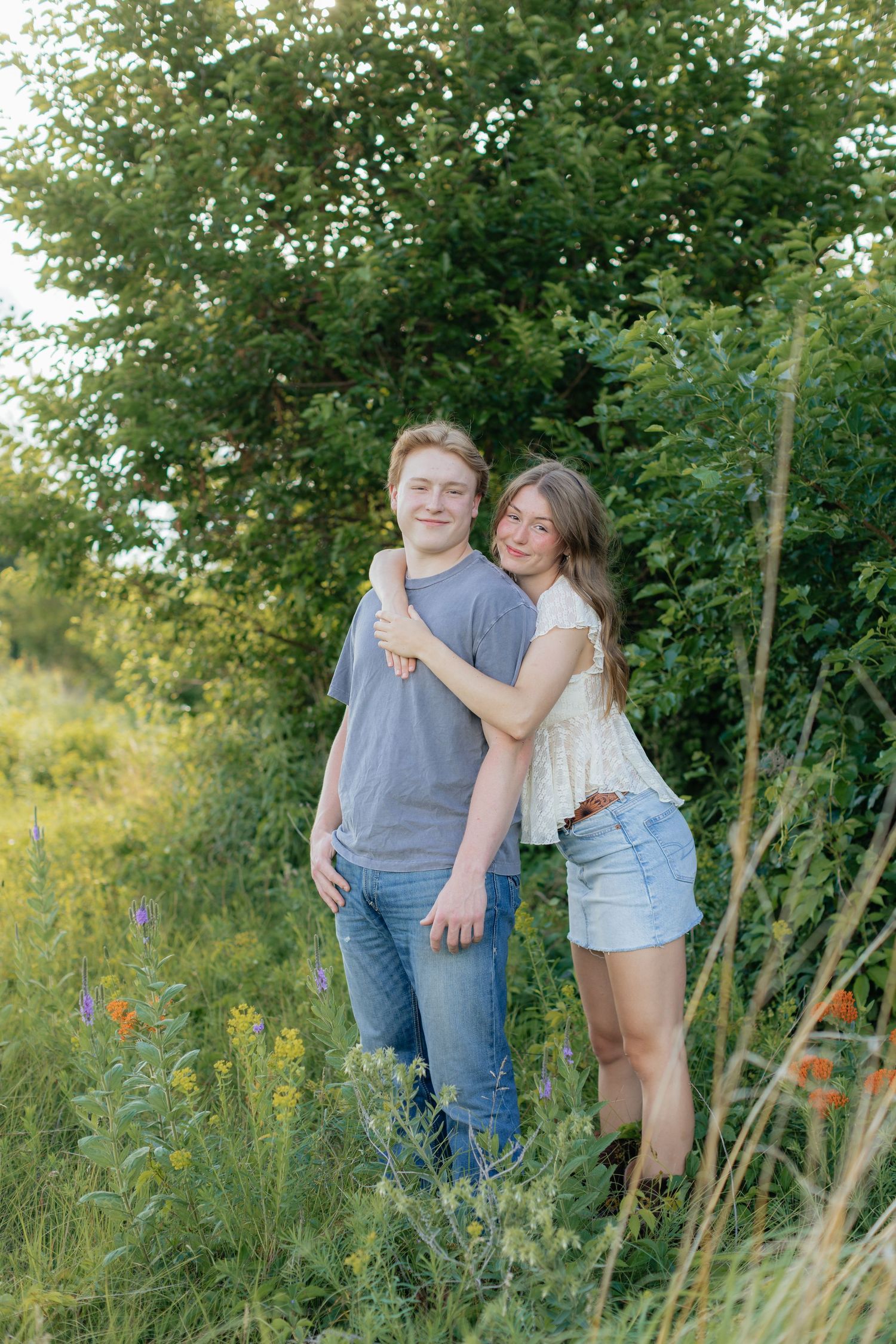 Romantic photo of a couple embracing on a hilltop at Prairie Bluffs, surrounded by open fields and wide Minnesota skies.