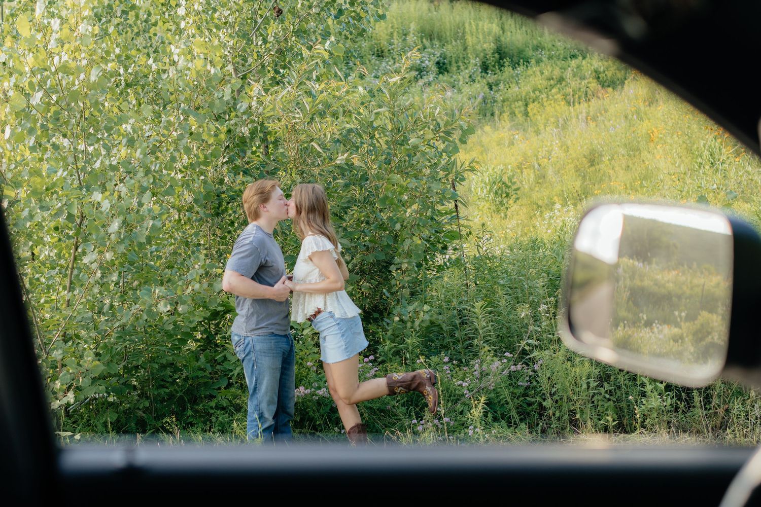 Romantic photo of a couple embracing on a hilltop at Prairie Bluffs, surrounded by open fields and wide Minnesota skies.