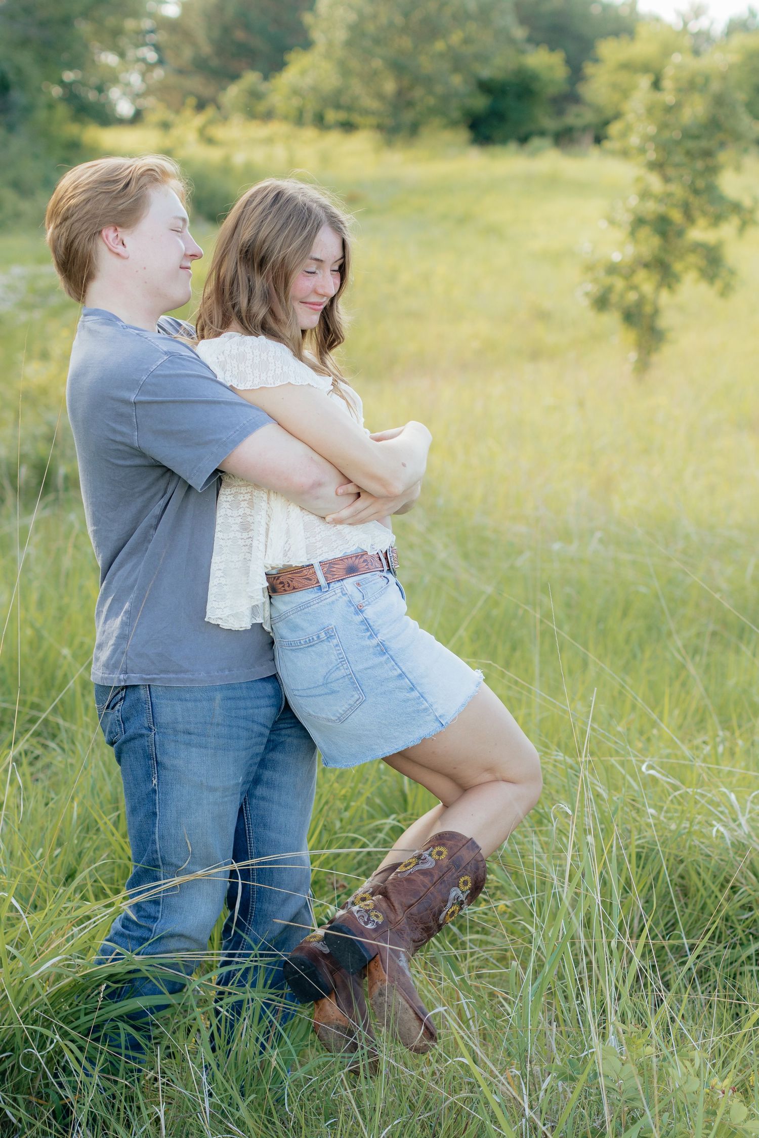 Romantic photo of a couple embracing on a hilltop at Prairie Bluffs, surrounded by open fields and wide Minnesota skies.