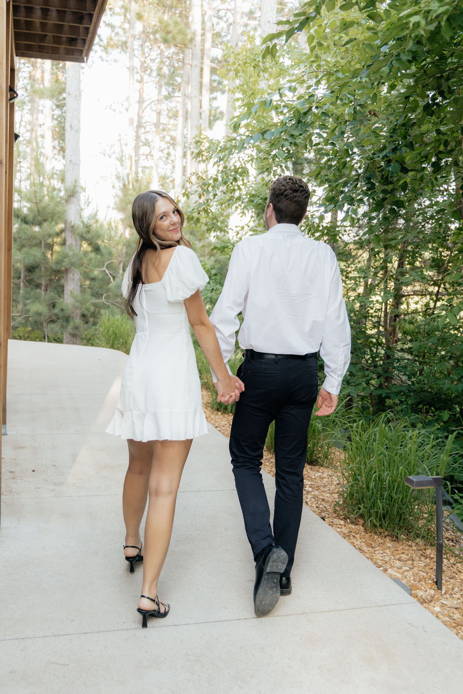 Golden-hour portrait of a couple embracing among tall trees at Pinewood in Cambridge, showcasing woodsy elegance.