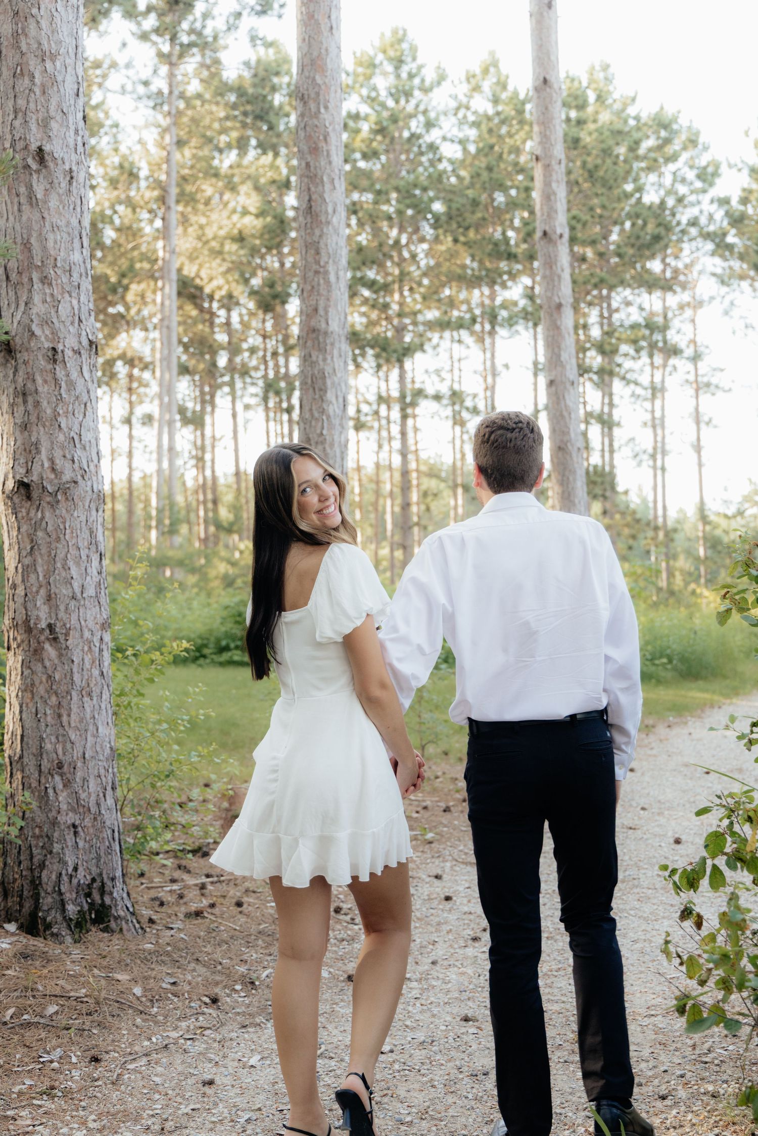Golden-hour portrait of a couple embracing among tall trees at Pinewood in Cambridge, showcasing woodsy elegance.