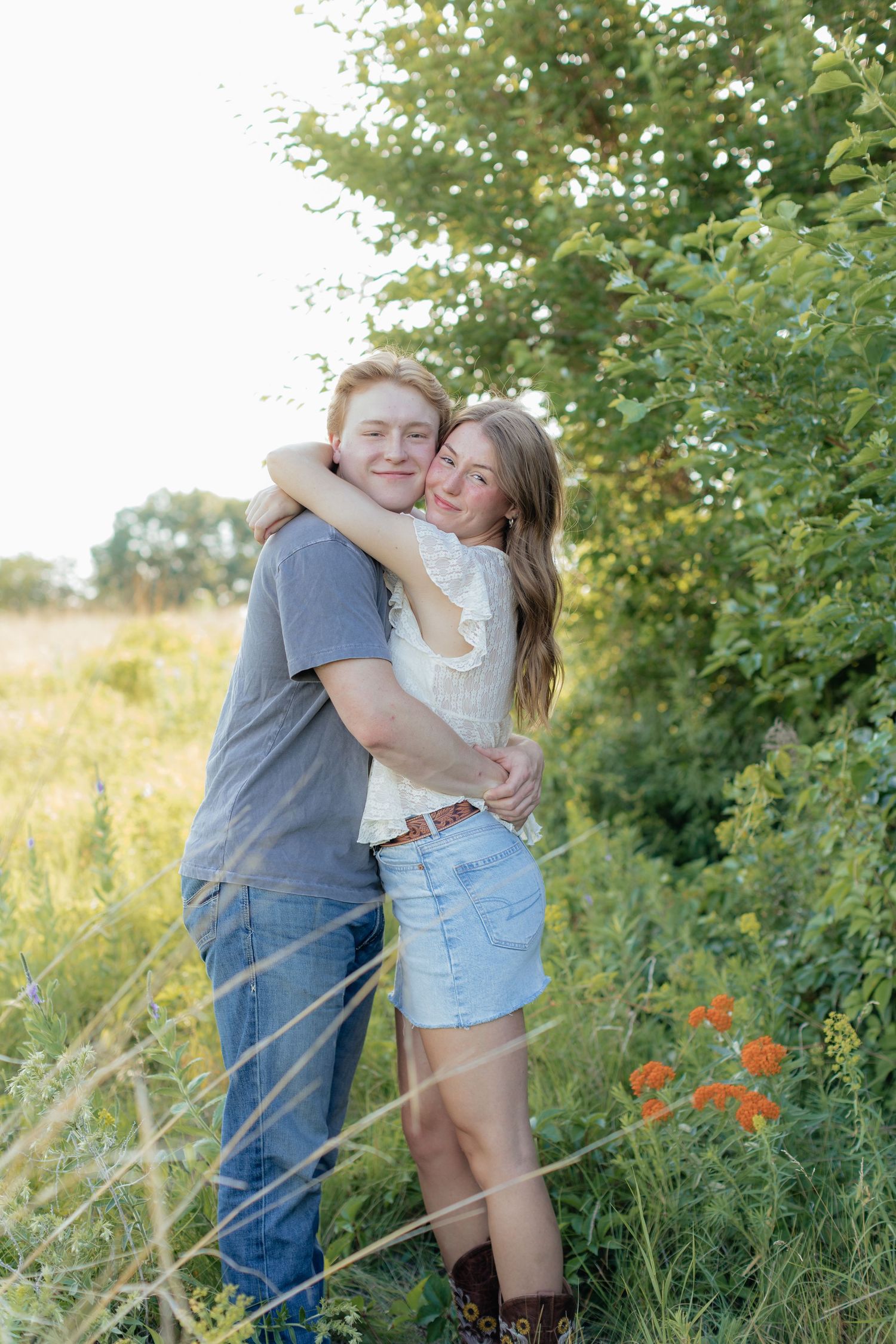 Romantic photo of a couple embracing on a hilltop at Prairie Bluffs, surrounded by open fields and wide Minnesota skies.