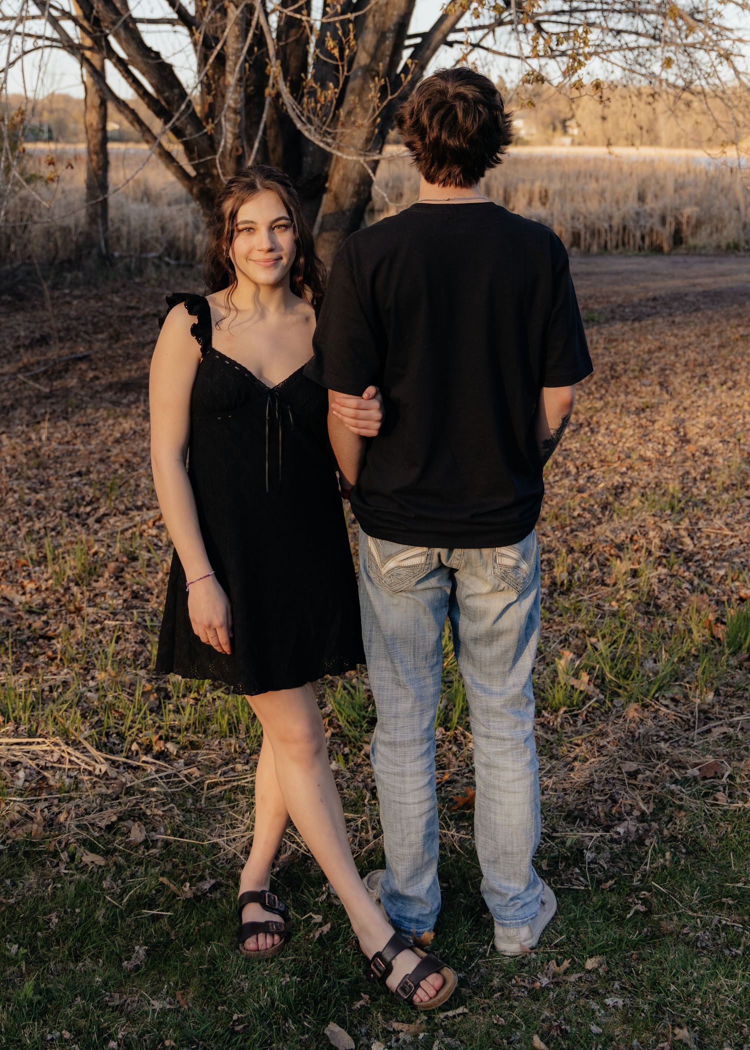 Couple laughing enjoying the blooming trees at Fish Lake Regional Park in Maple Grove, MN, with fresh green grass and soft spring sunlight