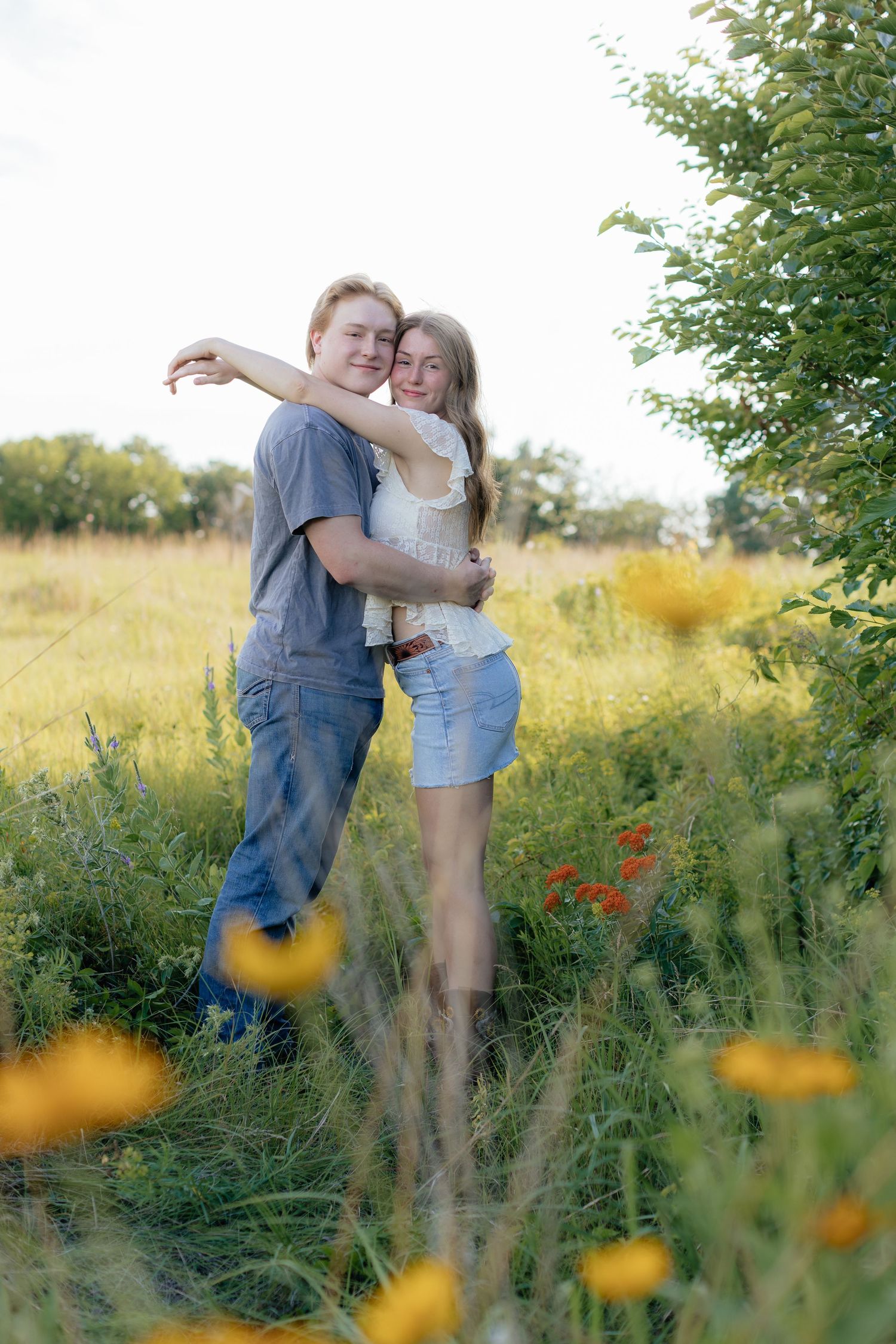 Romantic photo of a couple embracing on a hilltop at Prairie Bluffs, surrounded by open fields and wide Minnesota skies.