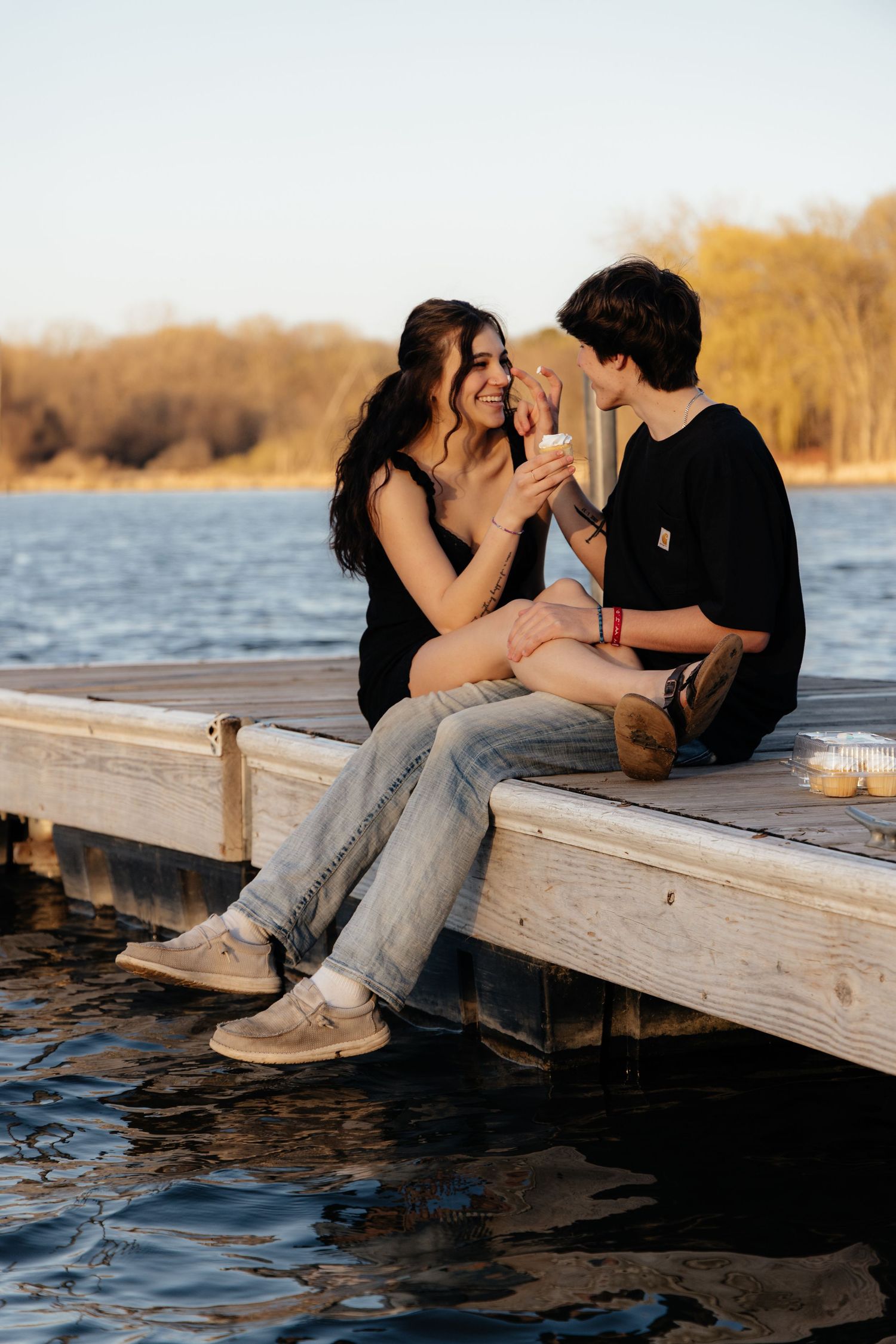 Couple laughing enjoying the blooming trees at Fish Lake Regional Park in Maple Grove, MN, with fresh green grass and soft spring sunlight