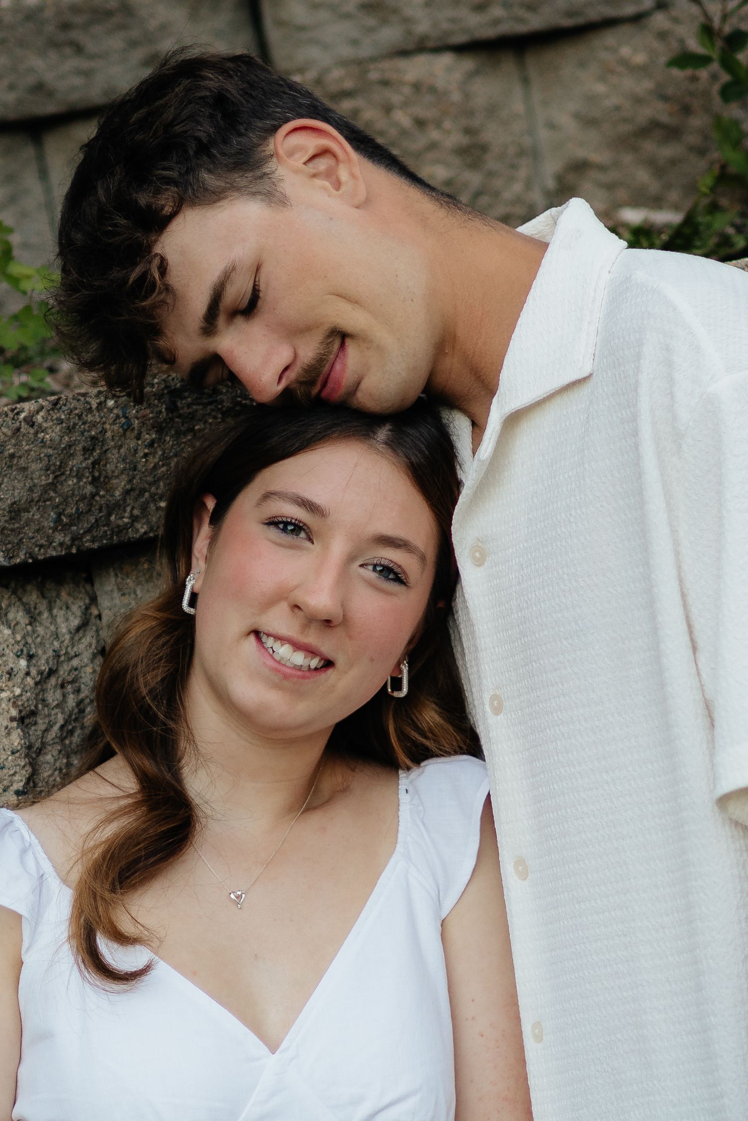 Couple smiling together along the lakeshore at Fish Lake Regional Park in Maple Grove, MN, with bright green trees and clear blue water