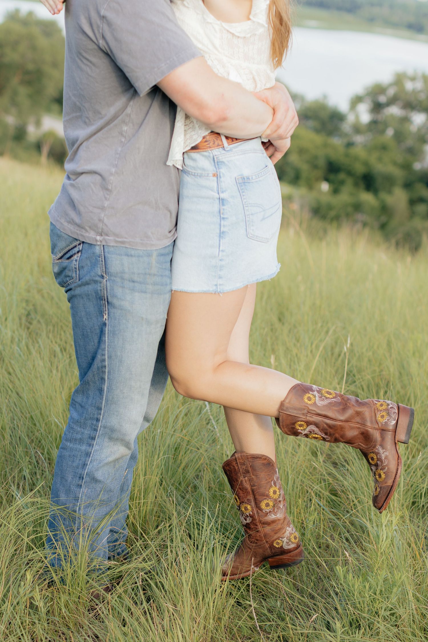 Romantic photo of a couple embracing on a hilltop at Prairie Bluffs, surrounded by open fields and wide Minnesota skies.