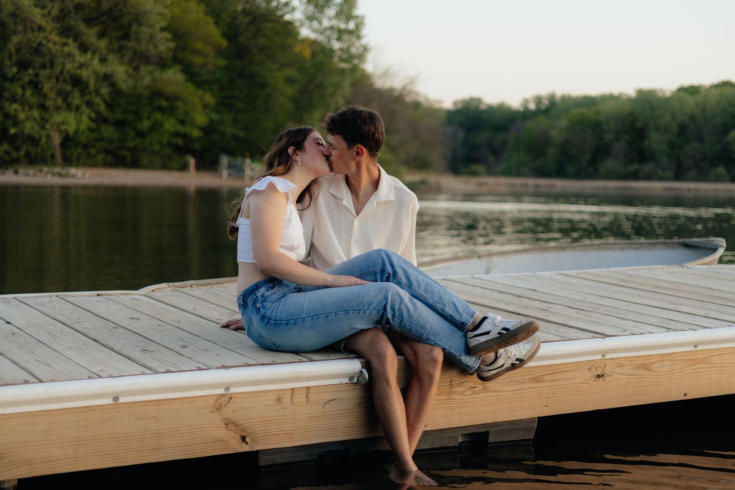Couple smiling together along the lakeshore at Fish Lake Regional Park in Maple Grove, MN, with bright green trees, clear blue water