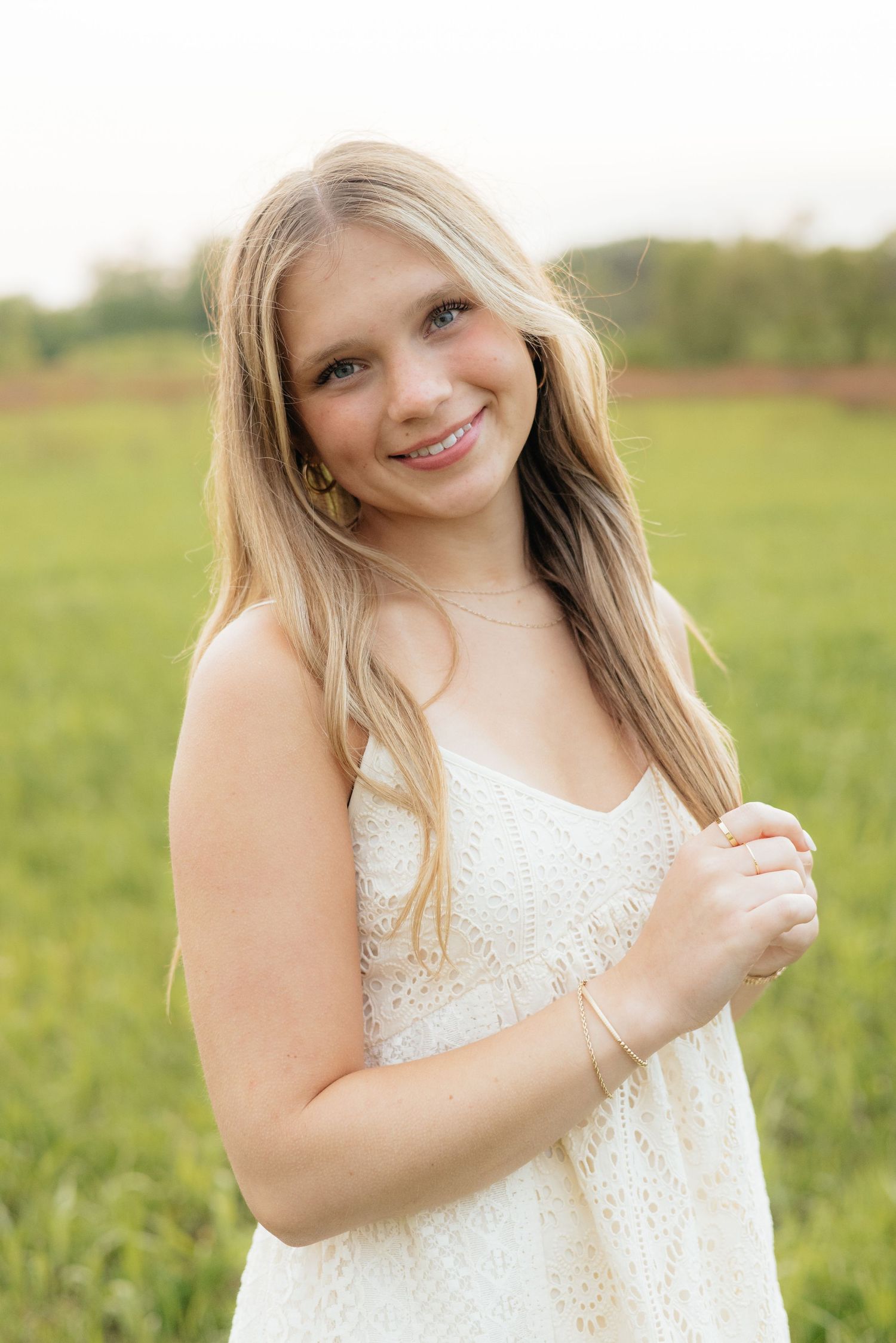 High school senior smiling and posing among blooming roses at Lyndale Park Rose Garden in Minneapolis, MN, surrounded by vibrant flowers and