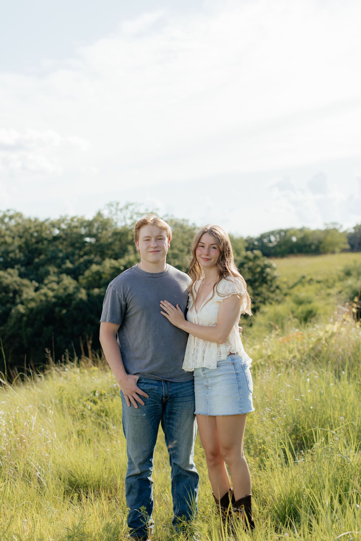 Romantic photo of a couple embracing on a hilltop at Prairie Bluffs, surrounded by open fields and wide Minnesota skies.