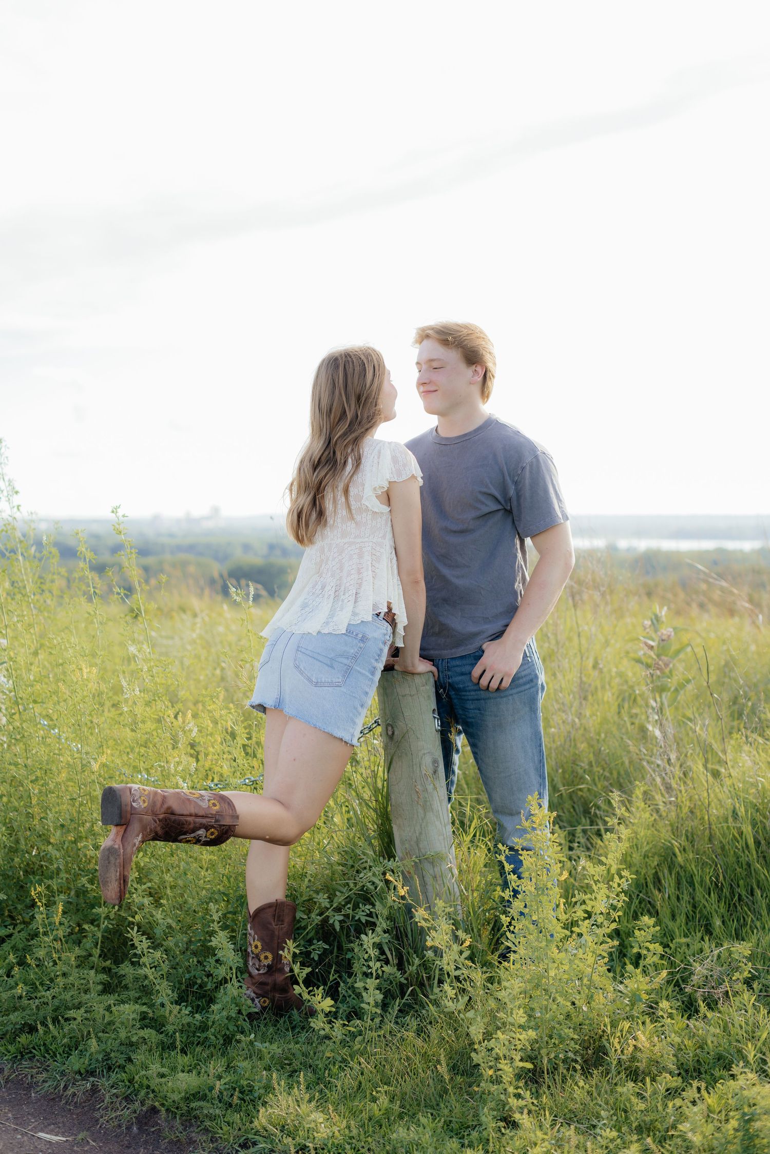 Romantic photo of a couple embracing on a hilltop at Prairie Bluffs, surrounded by open fields and wide Minnesota skies.
