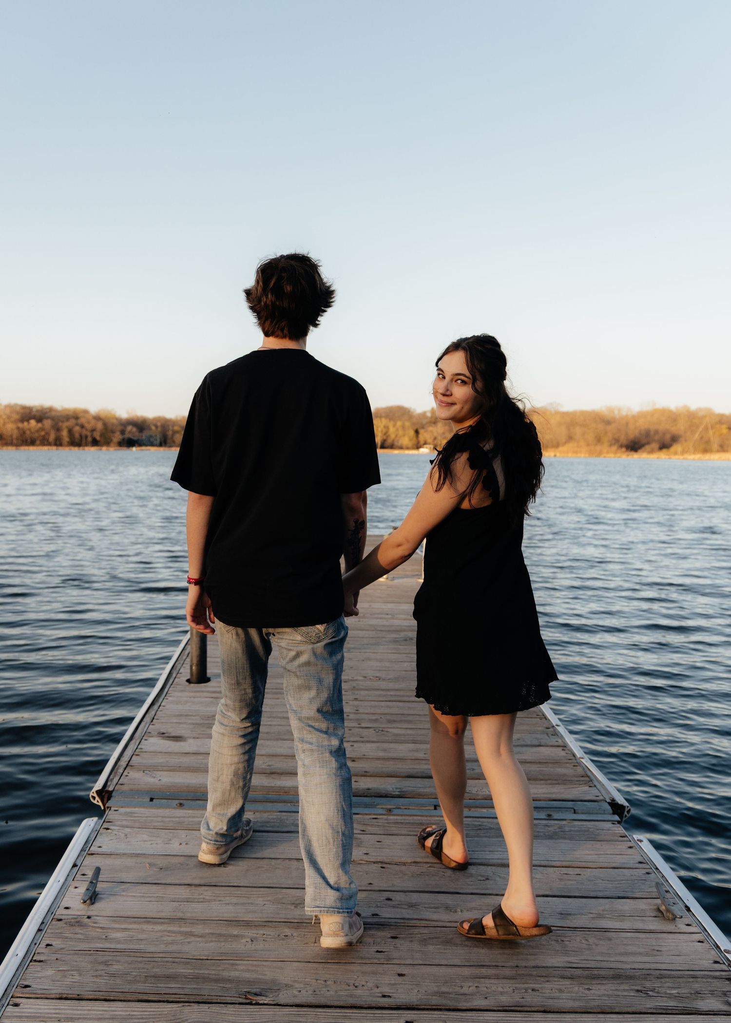 Couple laughing enjoying the blooming trees at Fish Lake Regional Park in Maple Grove, MN, with fresh green grass and soft spring sunlight