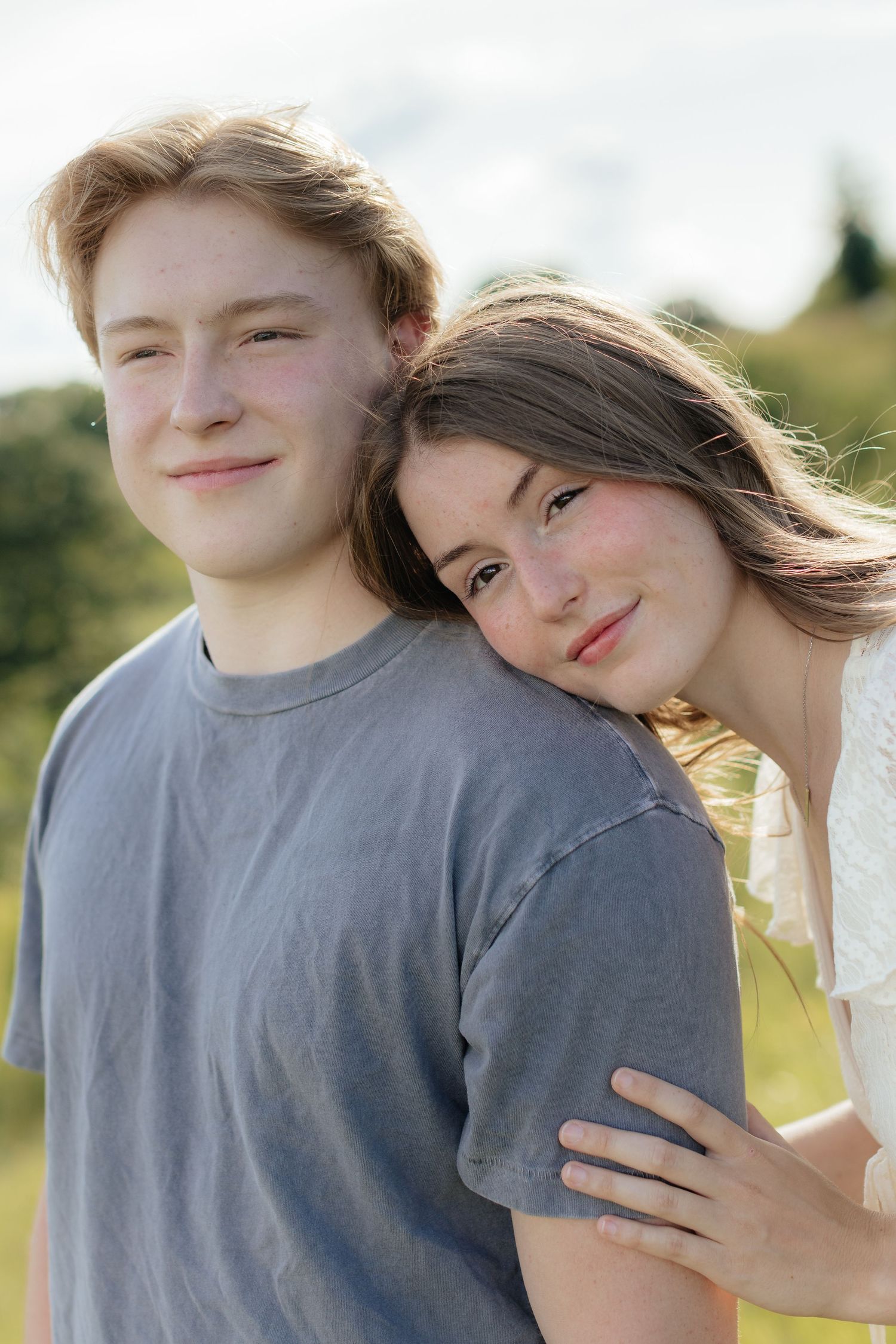 Romantic photo of a couple embracing on a hilltop at Prairie Bluffs, surrounded by open fields and wide Minnesota skies.