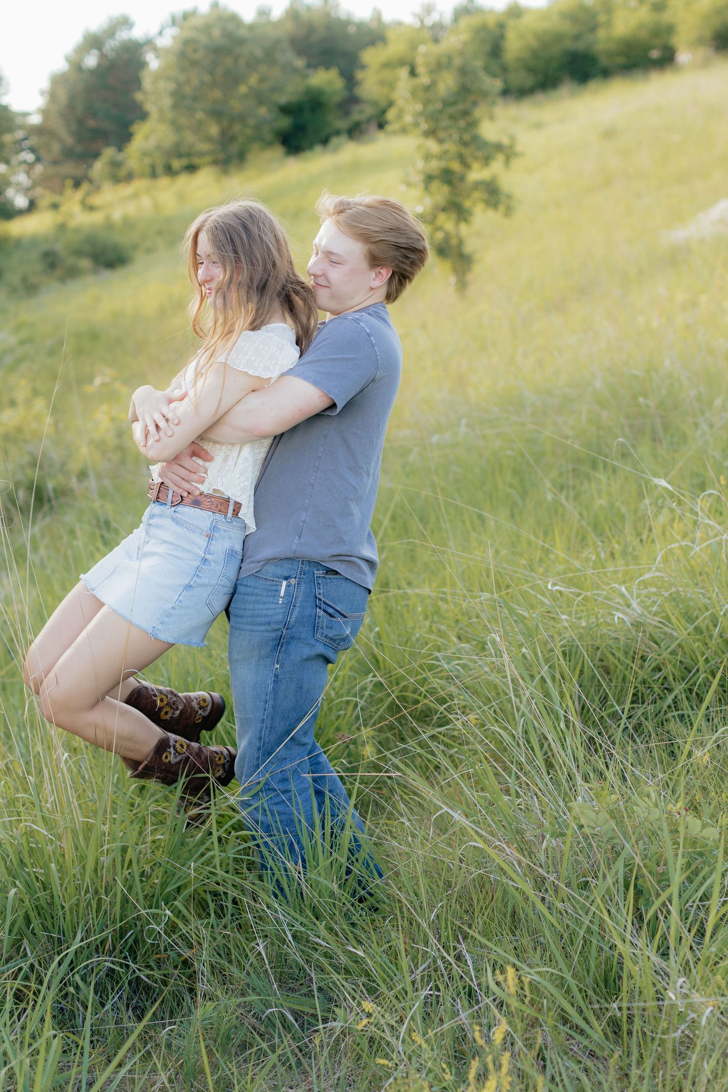 Romantic photo of a couple embracing on a hilltop at Prairie Bluffs, surrounded by open fields and wide Minnesota skies.