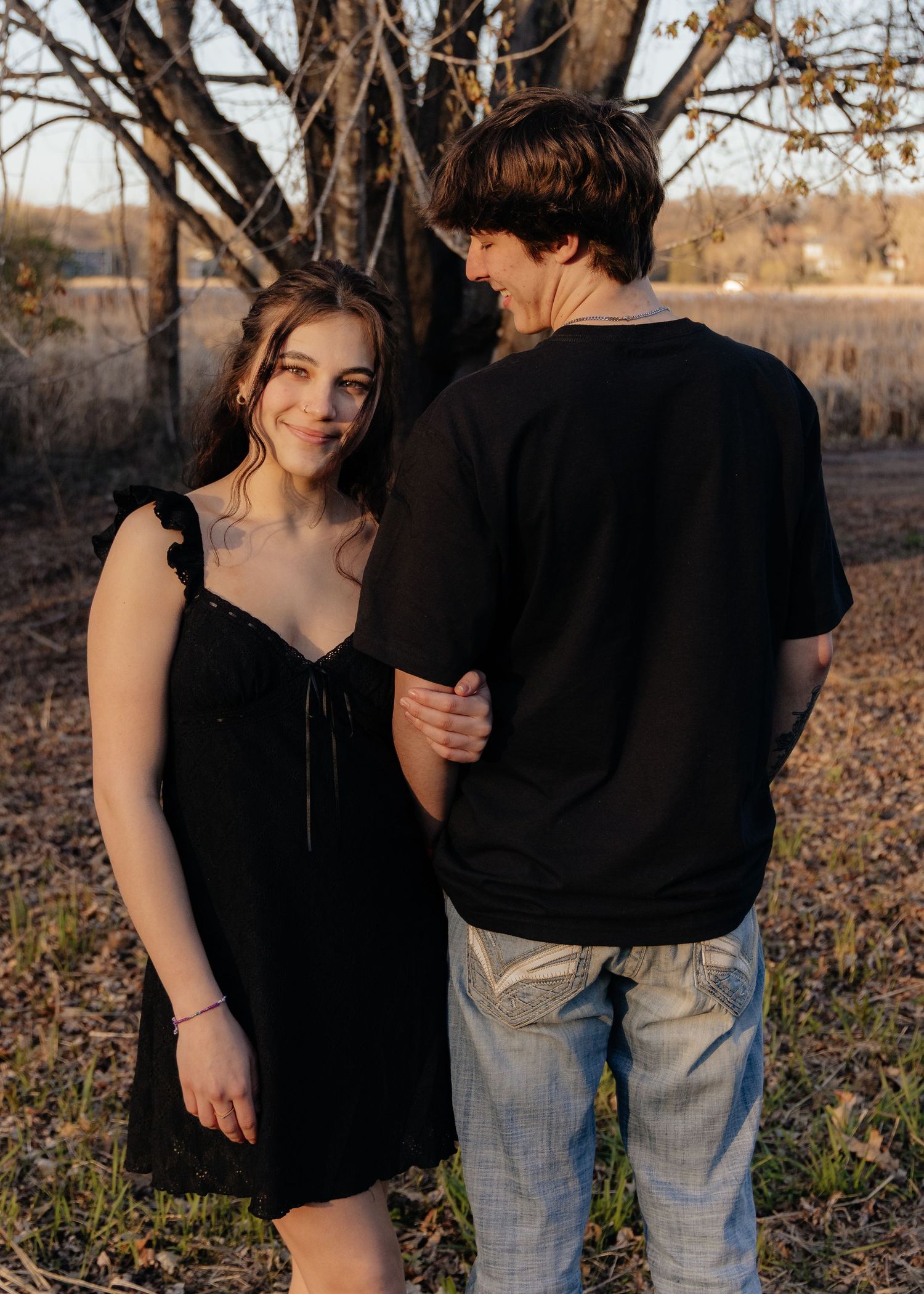 Couple laughing enjoying the blooming trees at Fish Lake Regional Park in Maple Grove, MN, with fresh green grass and soft spring sunlight