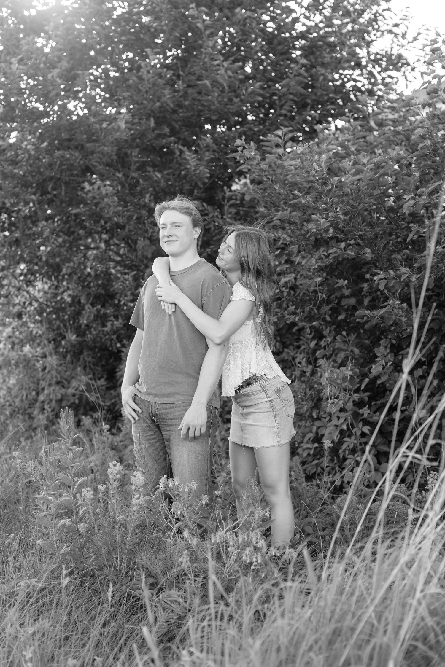 Romantic photo of a couple embracing on a hilltop at Prairie Bluffs, surrounded by open fields and wide Minnesota skies.