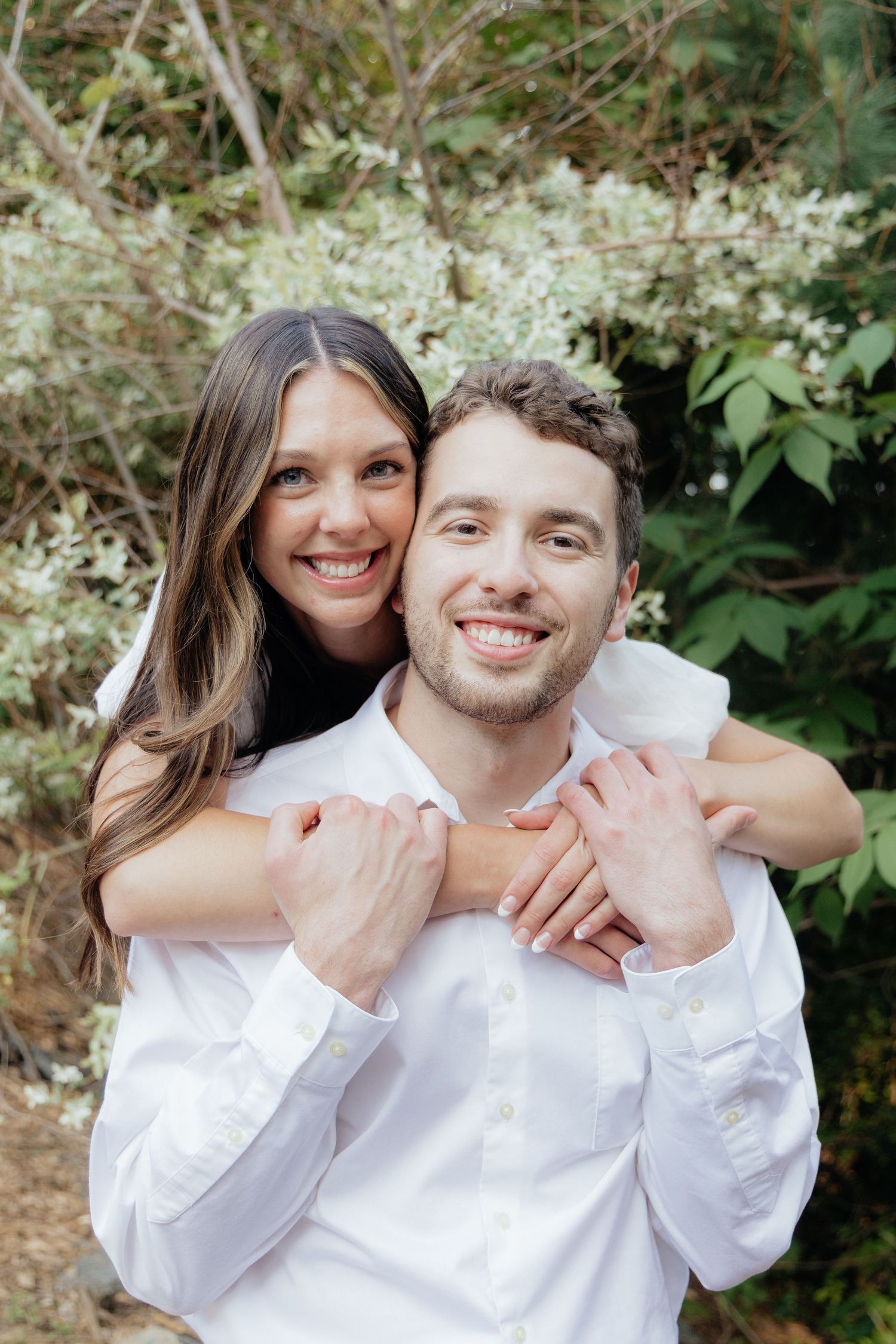 Golden-hour portrait of a couple embracing among tall trees at Pinewood in Cambridge, showcasing woodsy elegance.