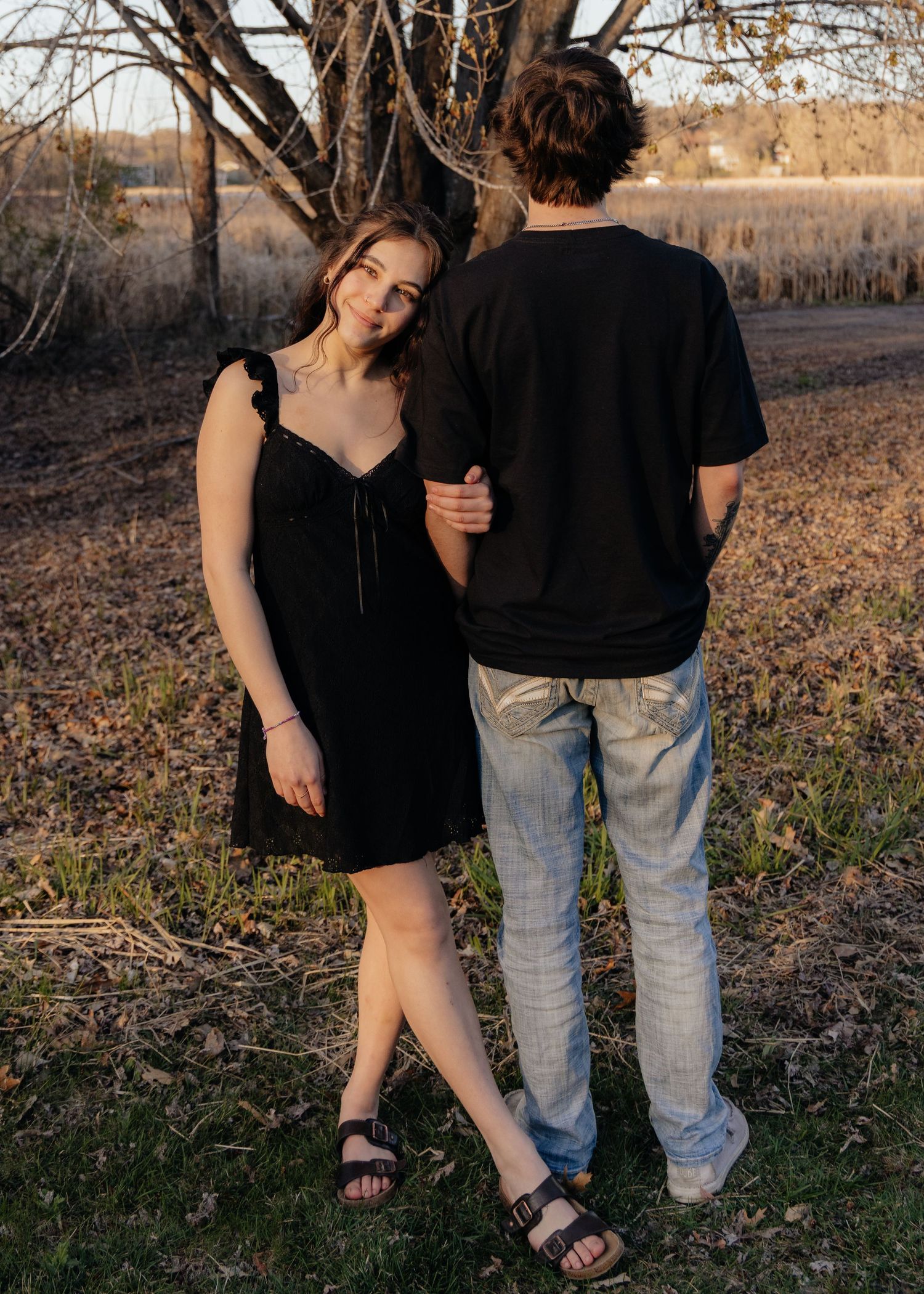 Couple laughing enjoying the blooming trees at Fish Lake Regional Park in Maple Grove, MN, with fresh green grass and soft spring sunlight