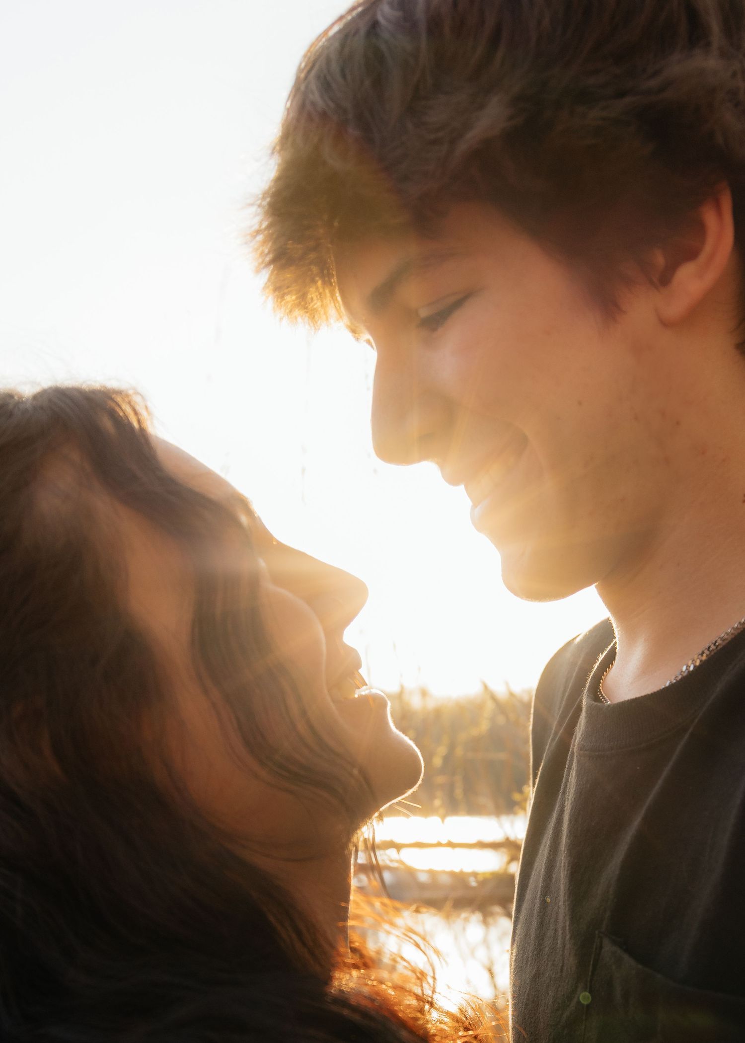 Couple laughing enjoying the blooming trees at Fish Lake Regional Park in Maple Grove, MN, with fresh green grass and soft spring sunlight