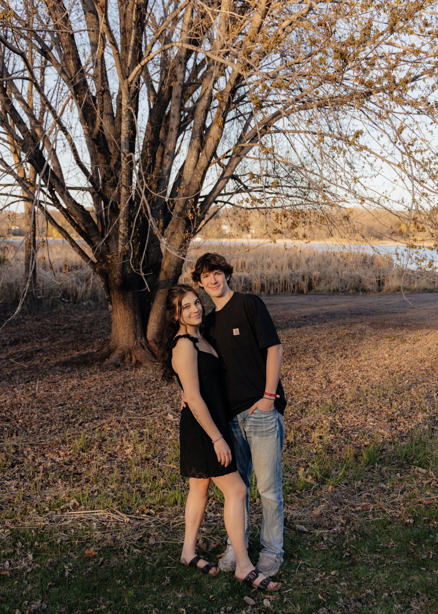 Couple laughing enjoying the blooming trees at Fish Lake Regional Park in Maple Grove, MN, with fresh green grass and soft spring sunlight