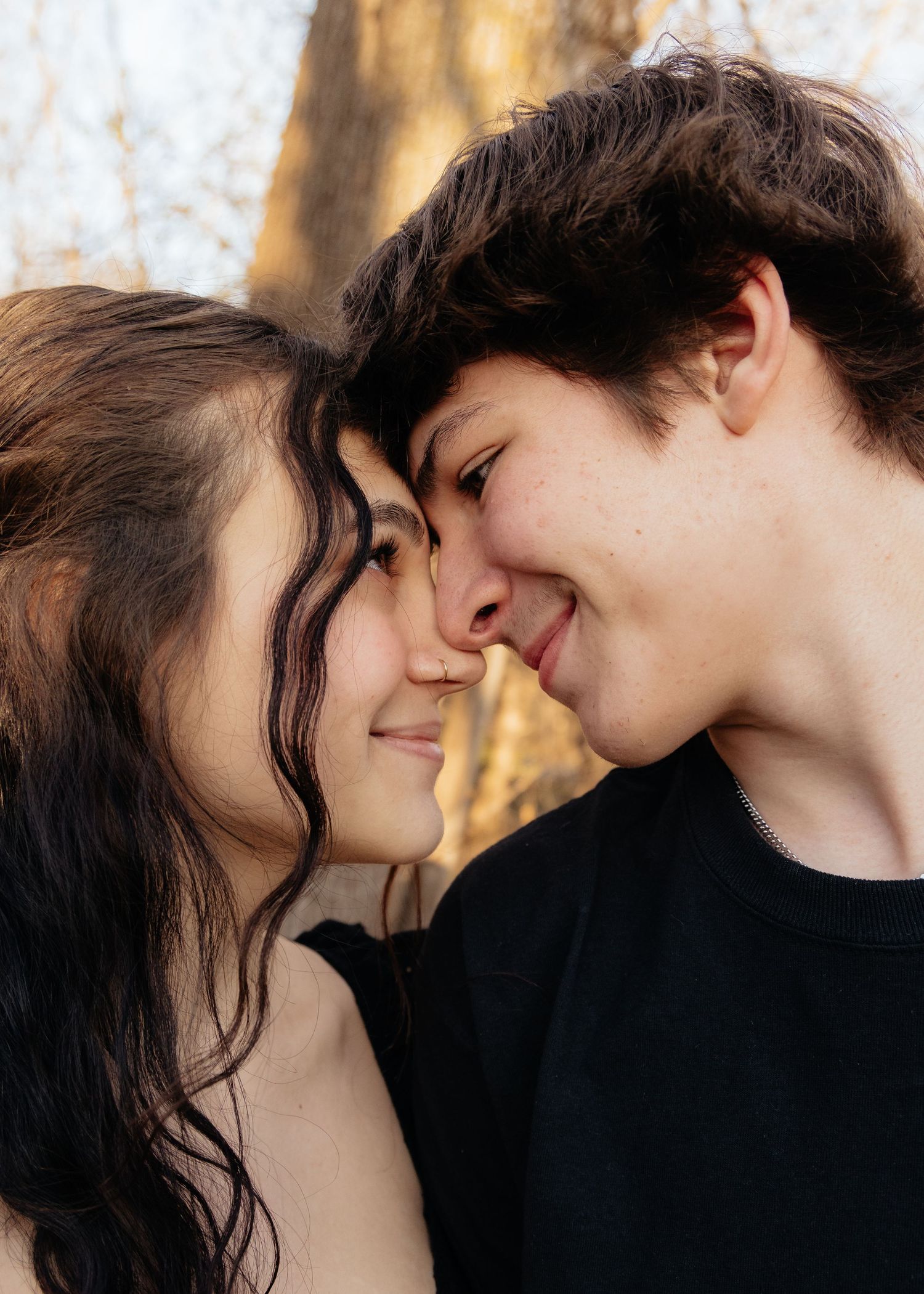 Couple laughing enjoying the blooming trees at Fish Lake Regional Park in Maple Grove, MN, with fresh green grass and soft spring sunlight