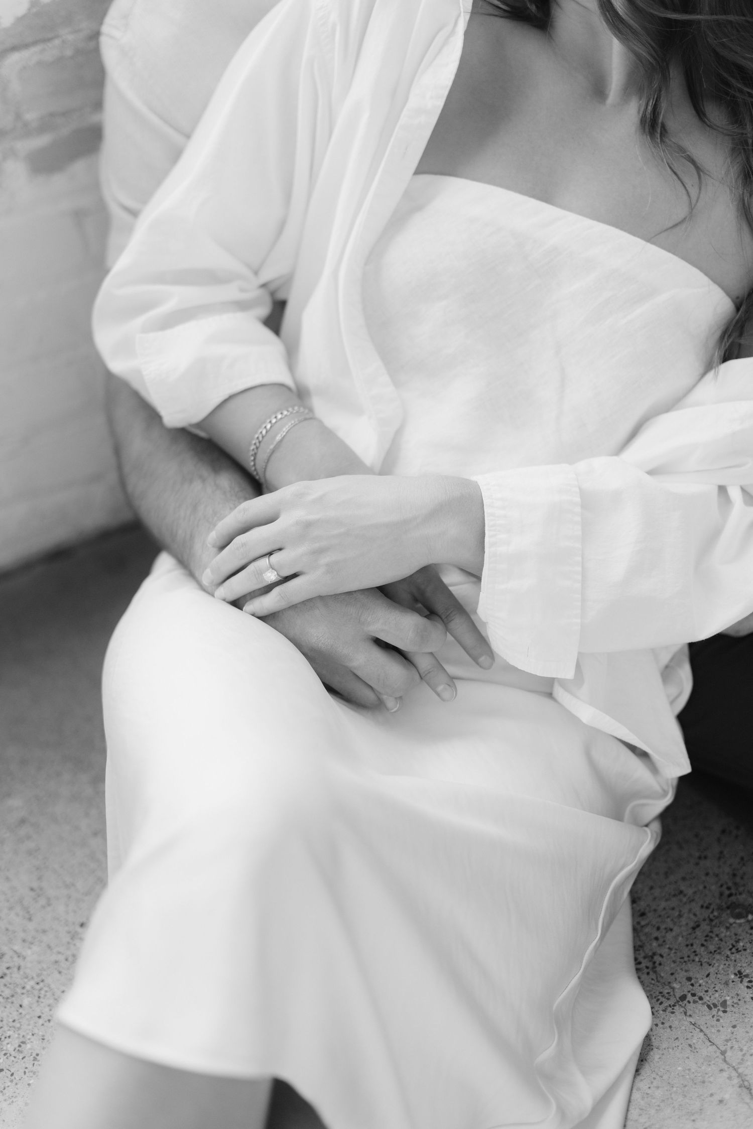 Couple embracing in soft natural light at Abide Studio in Minneapolis, MN, with minimalist white walls and warm, cozy tones