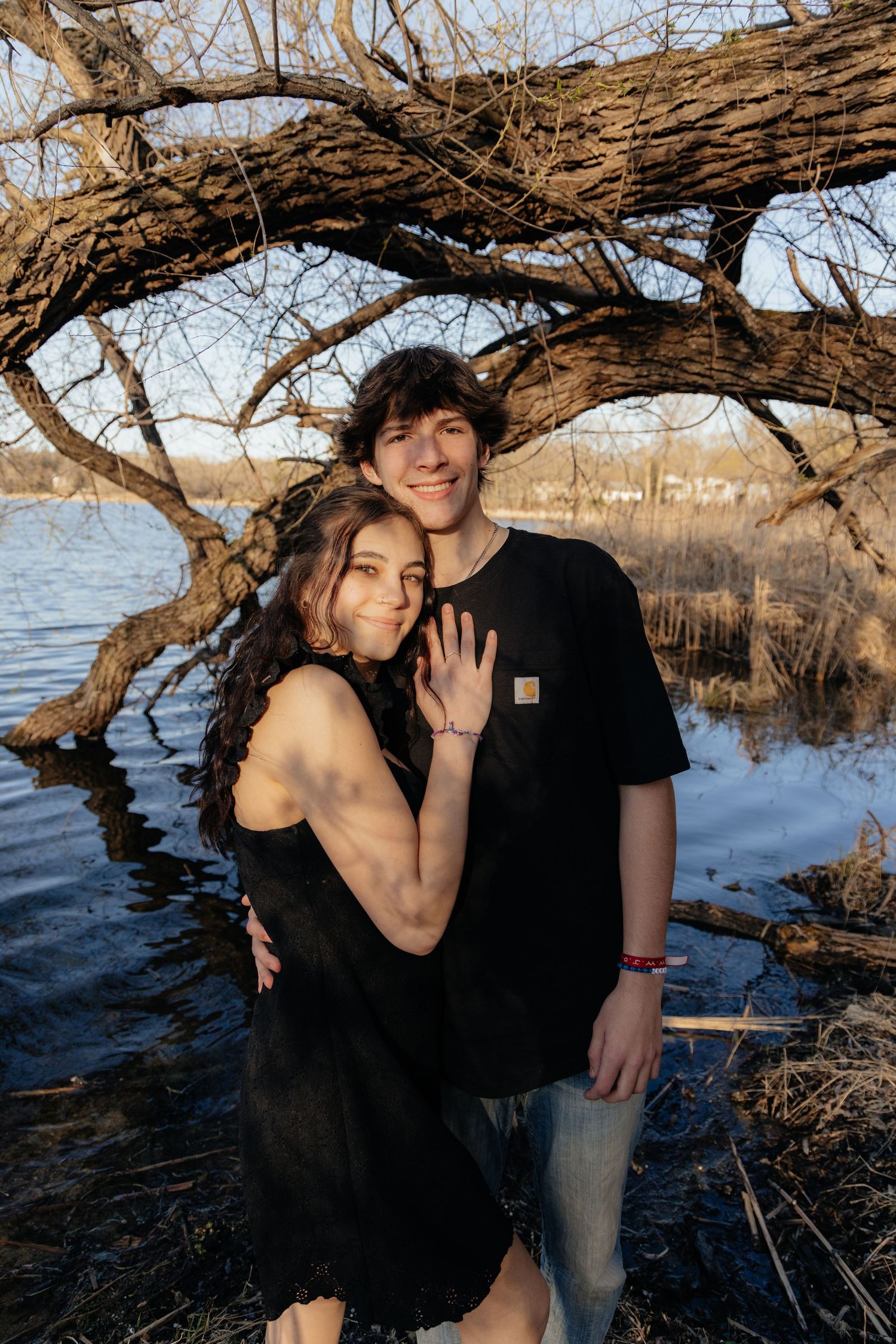 Couple laughing enjoying the blooming trees at Fish Lake Regional Park in Maple Grove, MN, with fresh green grass and soft spring sunlight