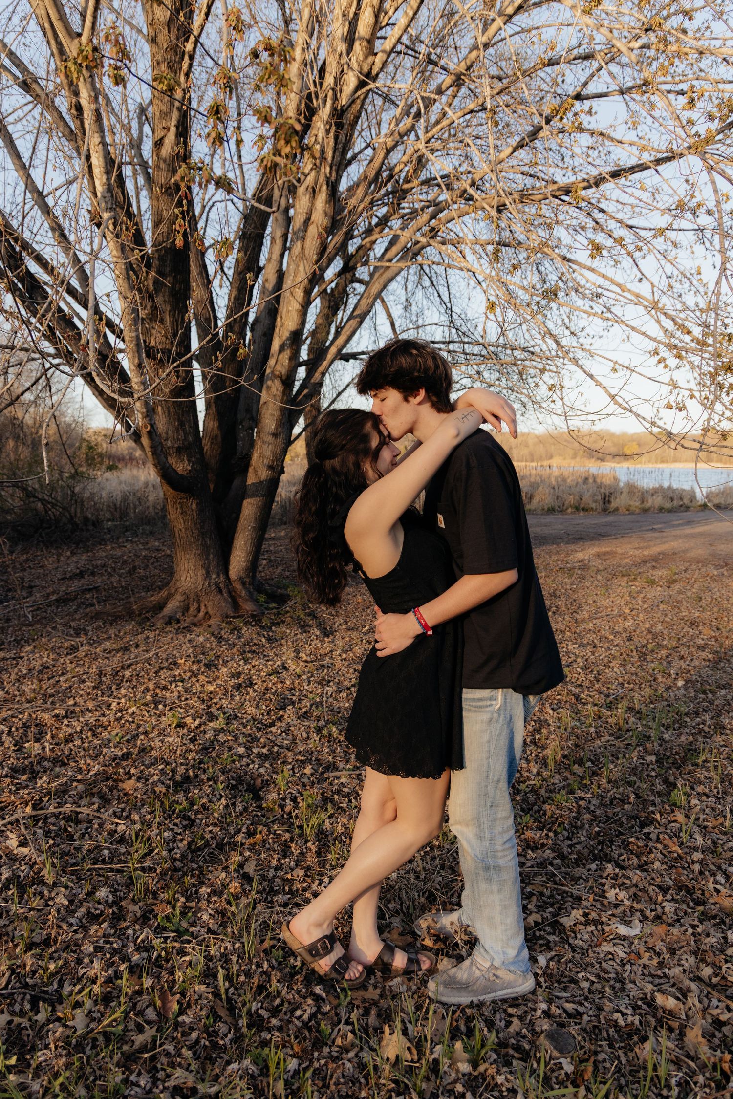Couple laughing enjoying the blooming trees at Fish Lake Regional Park in Maple Grove, MN, with fresh green grass and soft spring sunlight