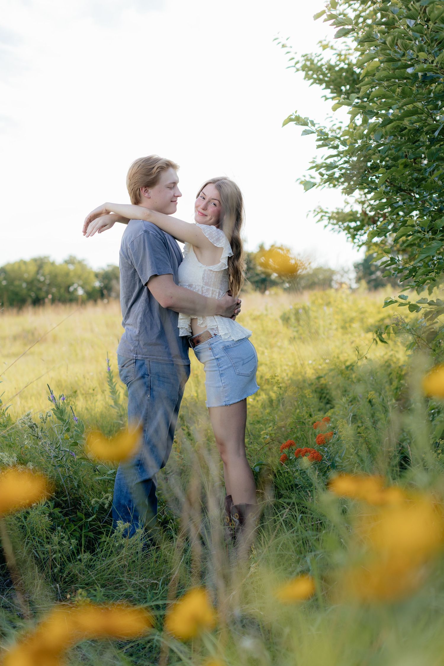 Romantic photo of a couple embracing on a hilltop at Prairie Bluffs, surrounded by open fields and wide Minnesota skies.