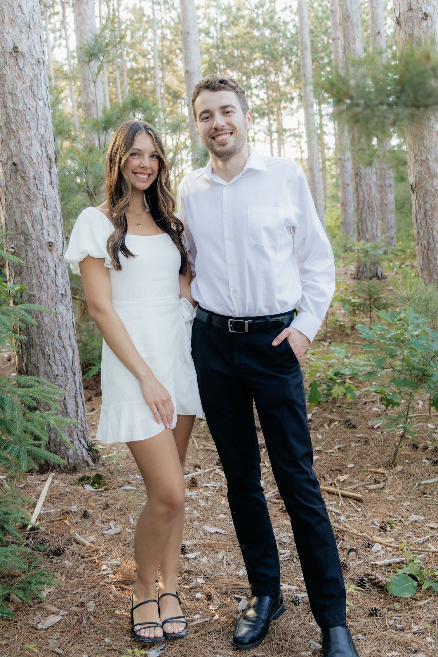 Golden-hour portrait of a couple embracing among tall trees at Pinewood in Cambridge, showcasing woodsy elegance.