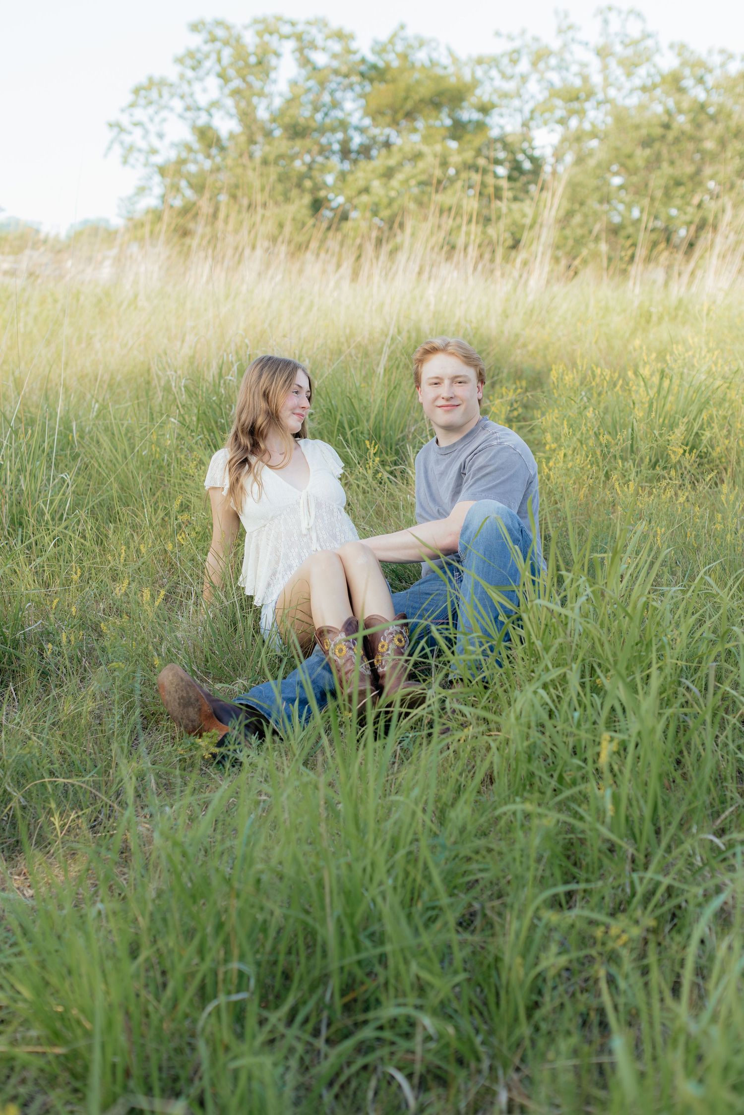 Romantic photo of a couple embracing on a hilltop at Prairie Bluffs, surrounded by open fields and wide Minnesota skies.