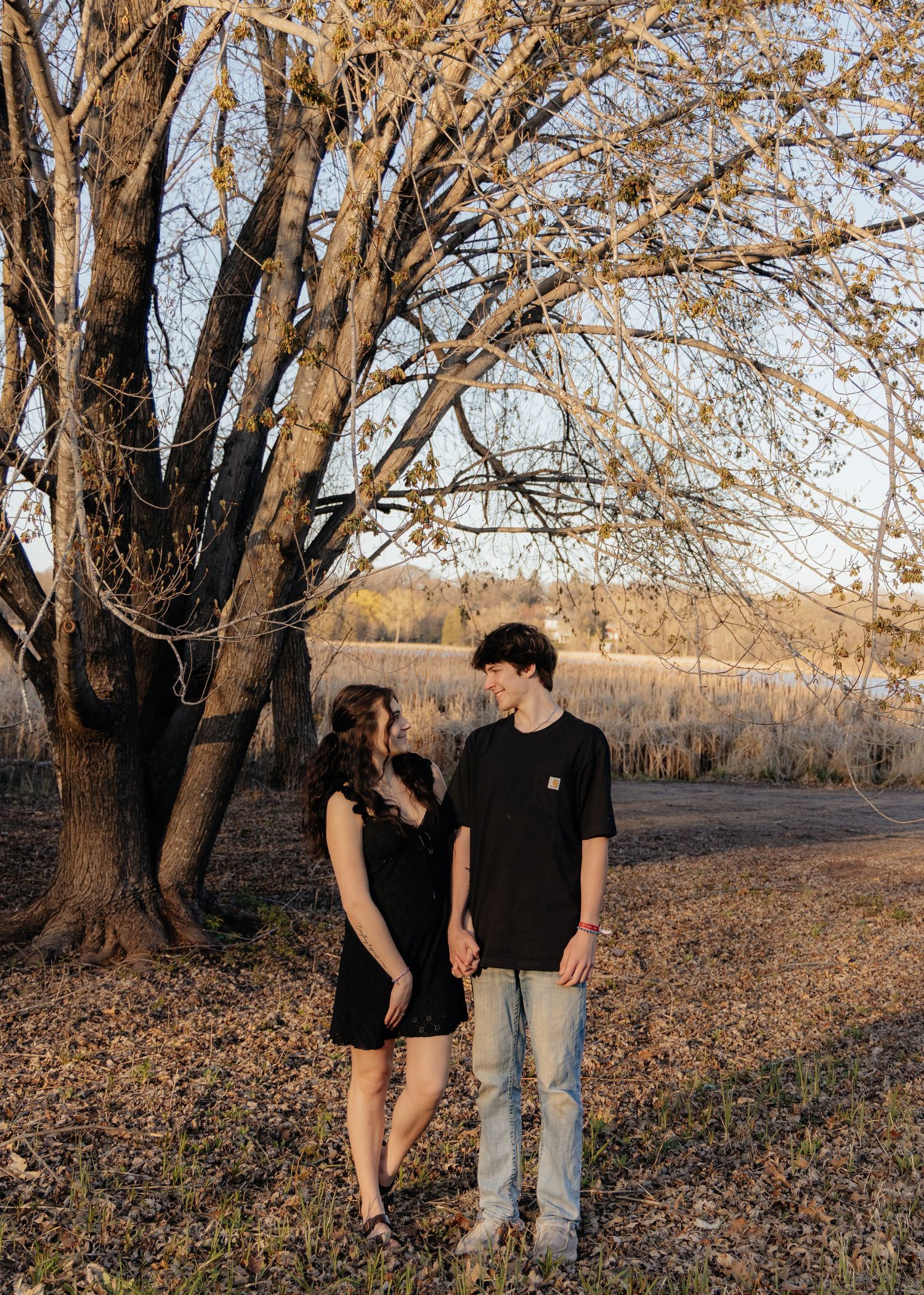 Couple laughing enjoying the blooming trees at Fish Lake Regional Park in Maple Grove, MN, with fresh green grass and soft spring sunlight
