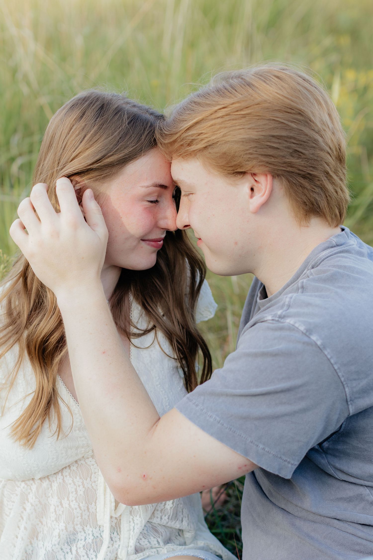 Romantic photo of a couple embracing on a hilltop at Prairie Bluffs, surrounded by open fields and wide Minnesota skies.