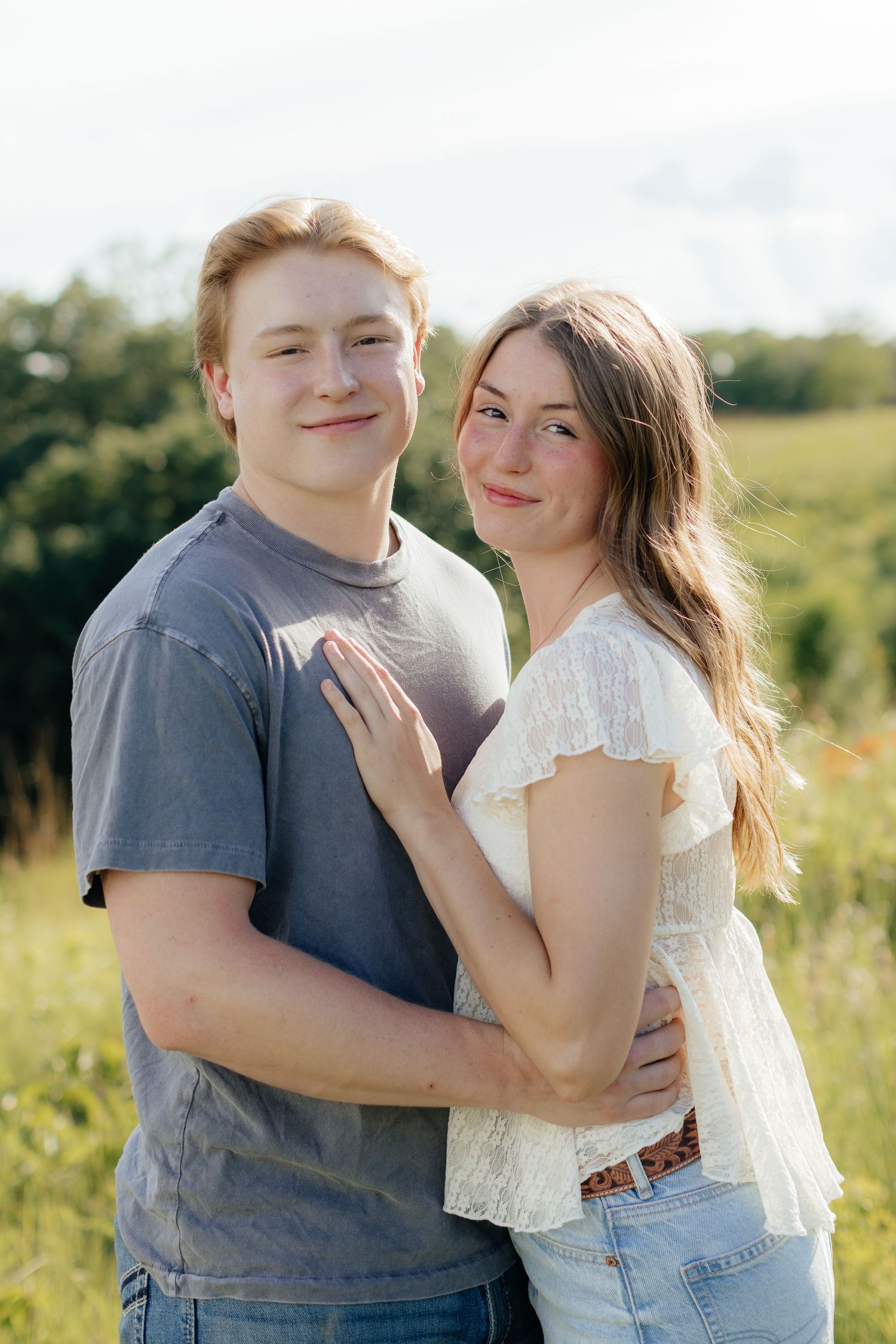 Romantic photo of a couple embracing on a hilltop at Prairie Bluffs, surrounded by open fields and wide Minnesota skies.