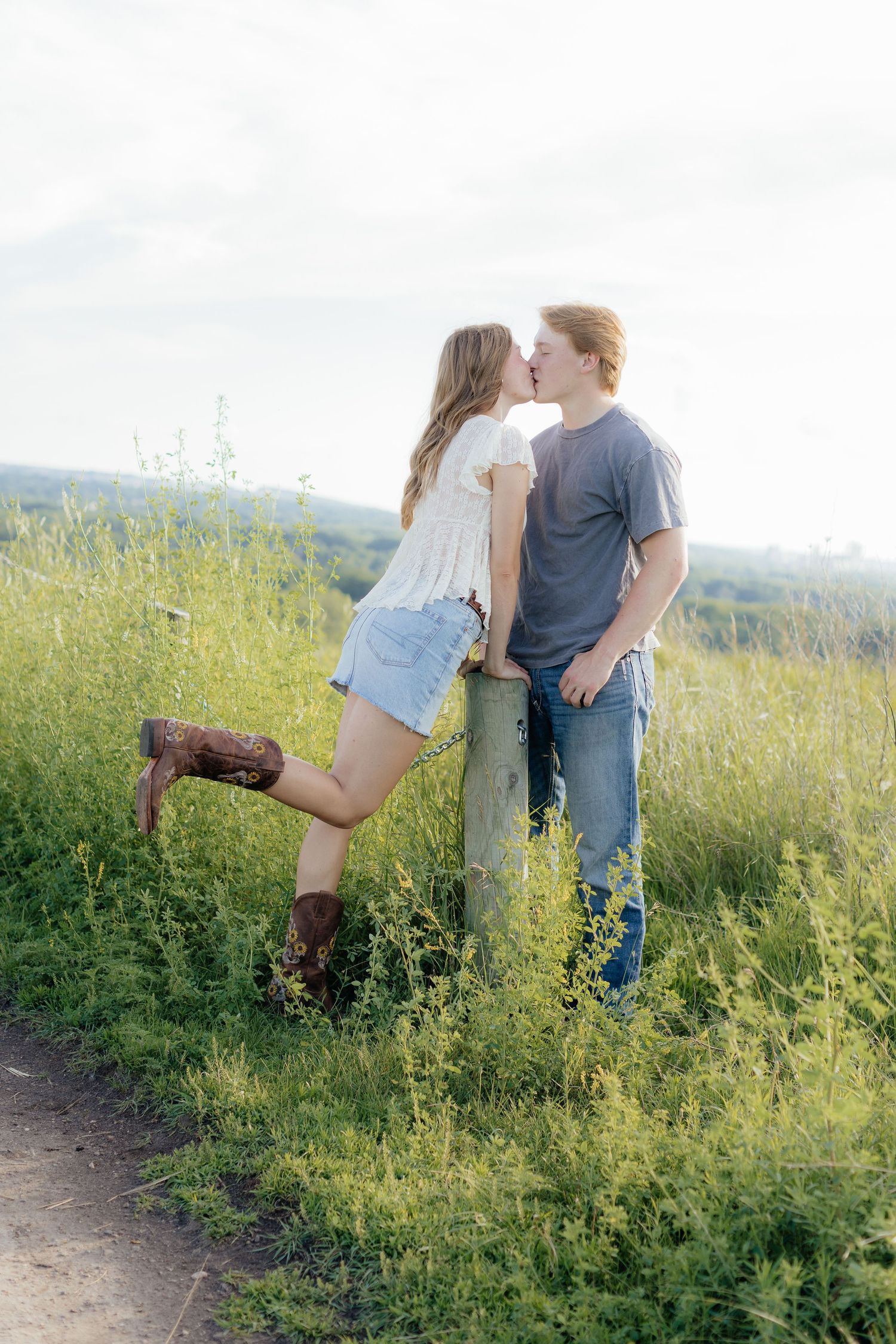 Romantic photo of a couple embracing on a hilltop at Prairie Bluffs, surrounded by open fields and wide Minnesota skies.