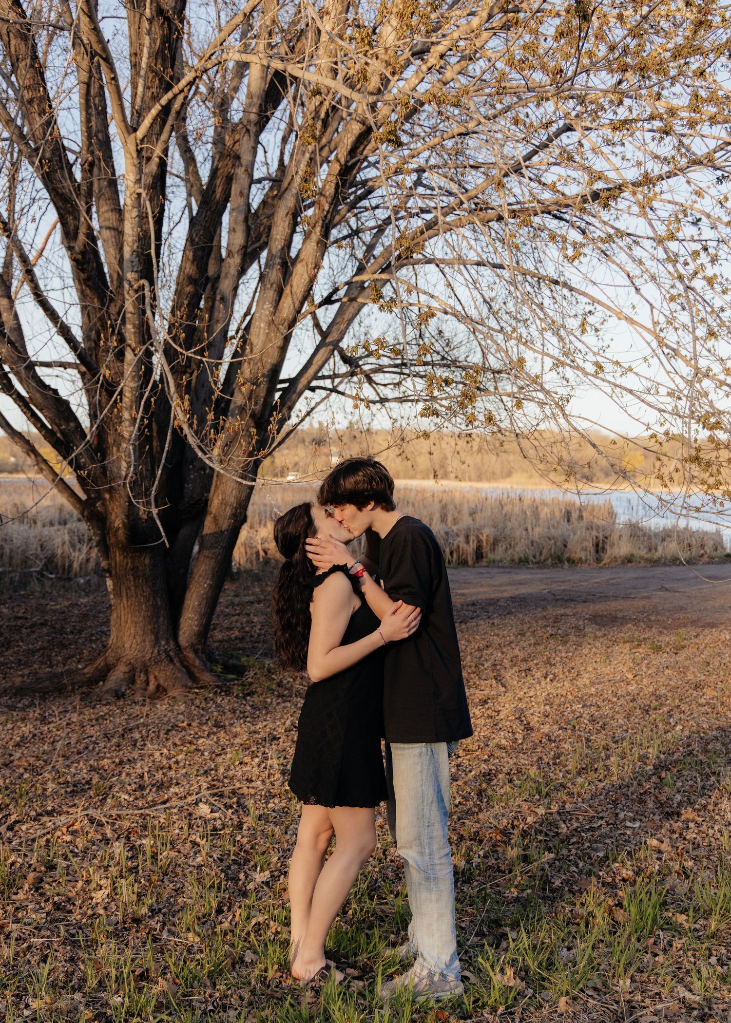Couple laughing enjoying the blooming trees at Fish Lake Regional Park in Maple Grove, MN, with fresh green grass and soft spring sunlight