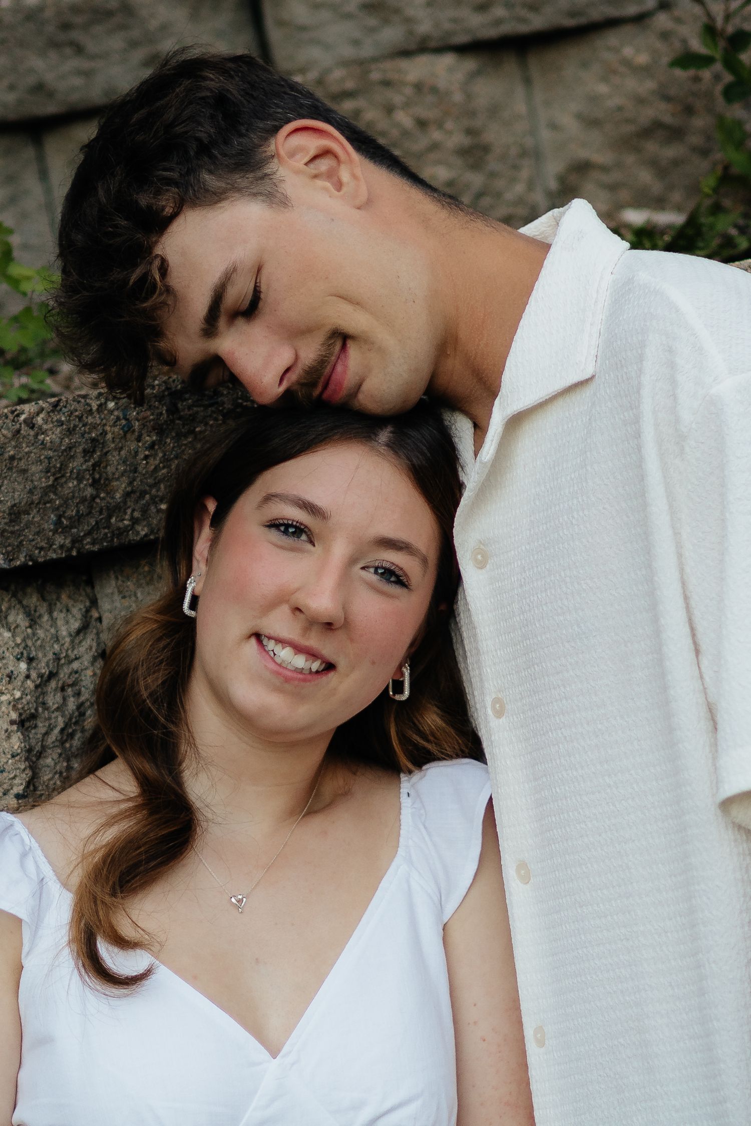 Couple smiling together along the lakeshore at Fish Lake Regional Park in Maple Grove, MN, with bright green trees and clear blue water