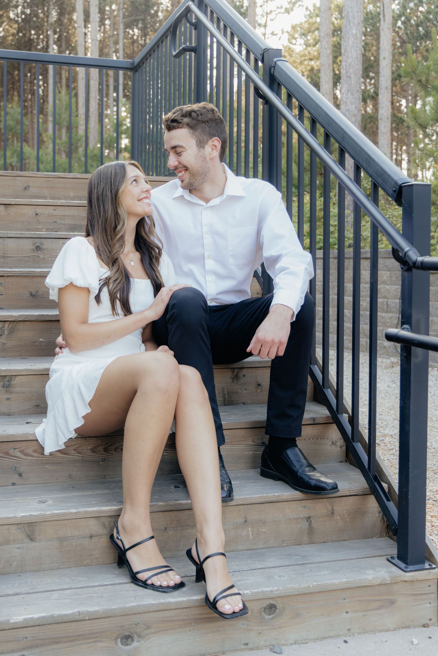 Golden-hour portrait of a couple embracing among tall trees at Pinewood in Cambridge, showcasing woodsy elegance.