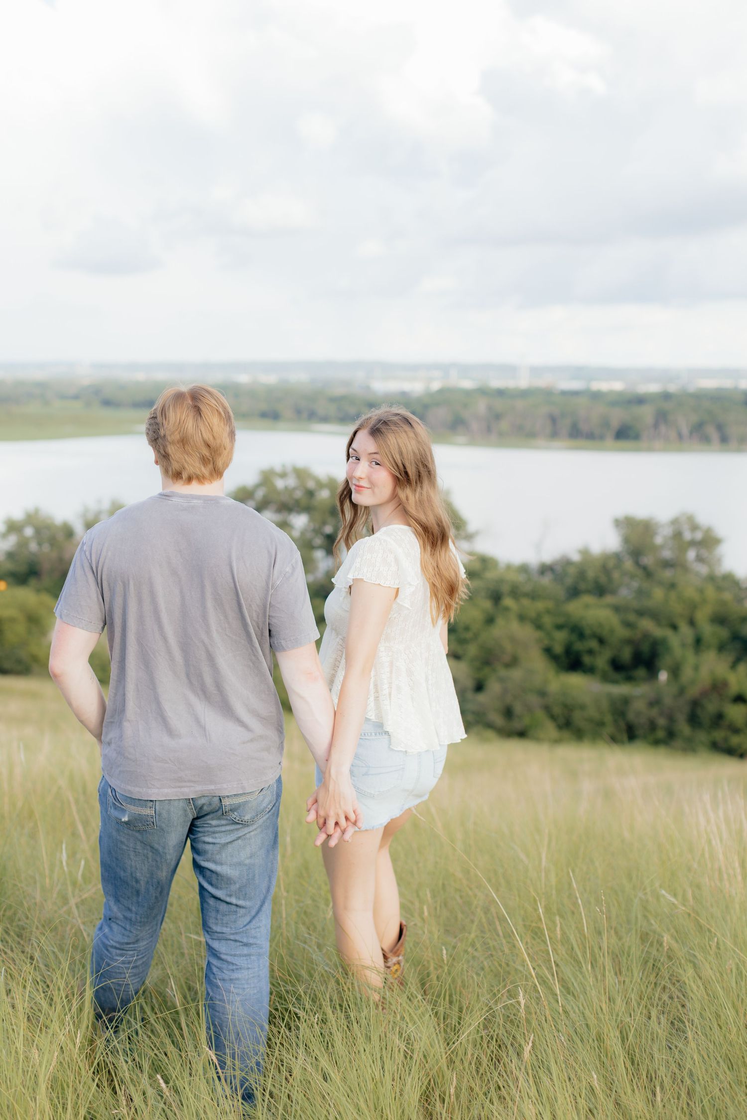 Romantic photo of a couple embracing on a hilltop at Prairie Bluffs, surrounded by open fields and wide Minnesota skies.